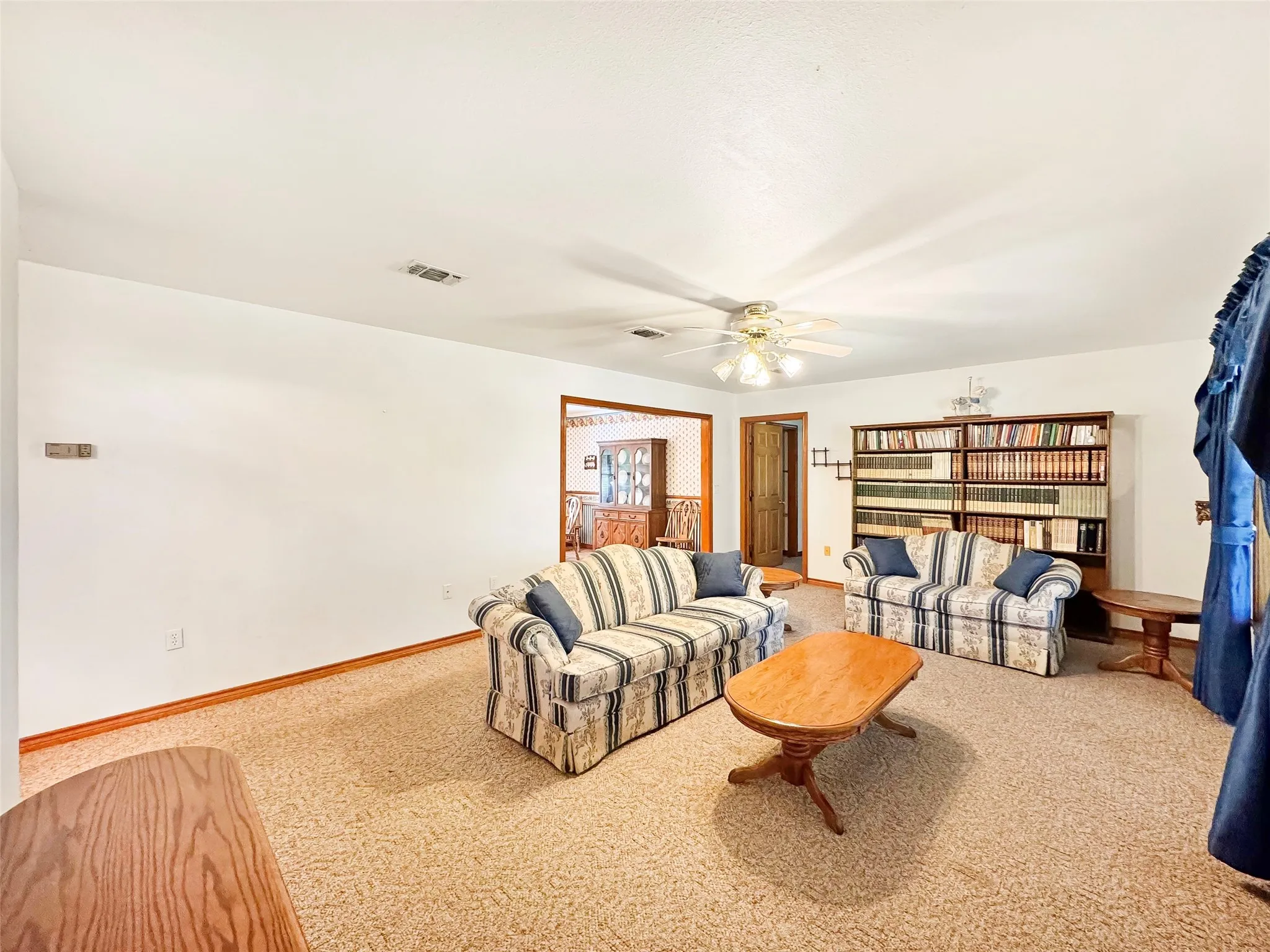 Spacious living area featuring neutral carpeting and white wall finishes