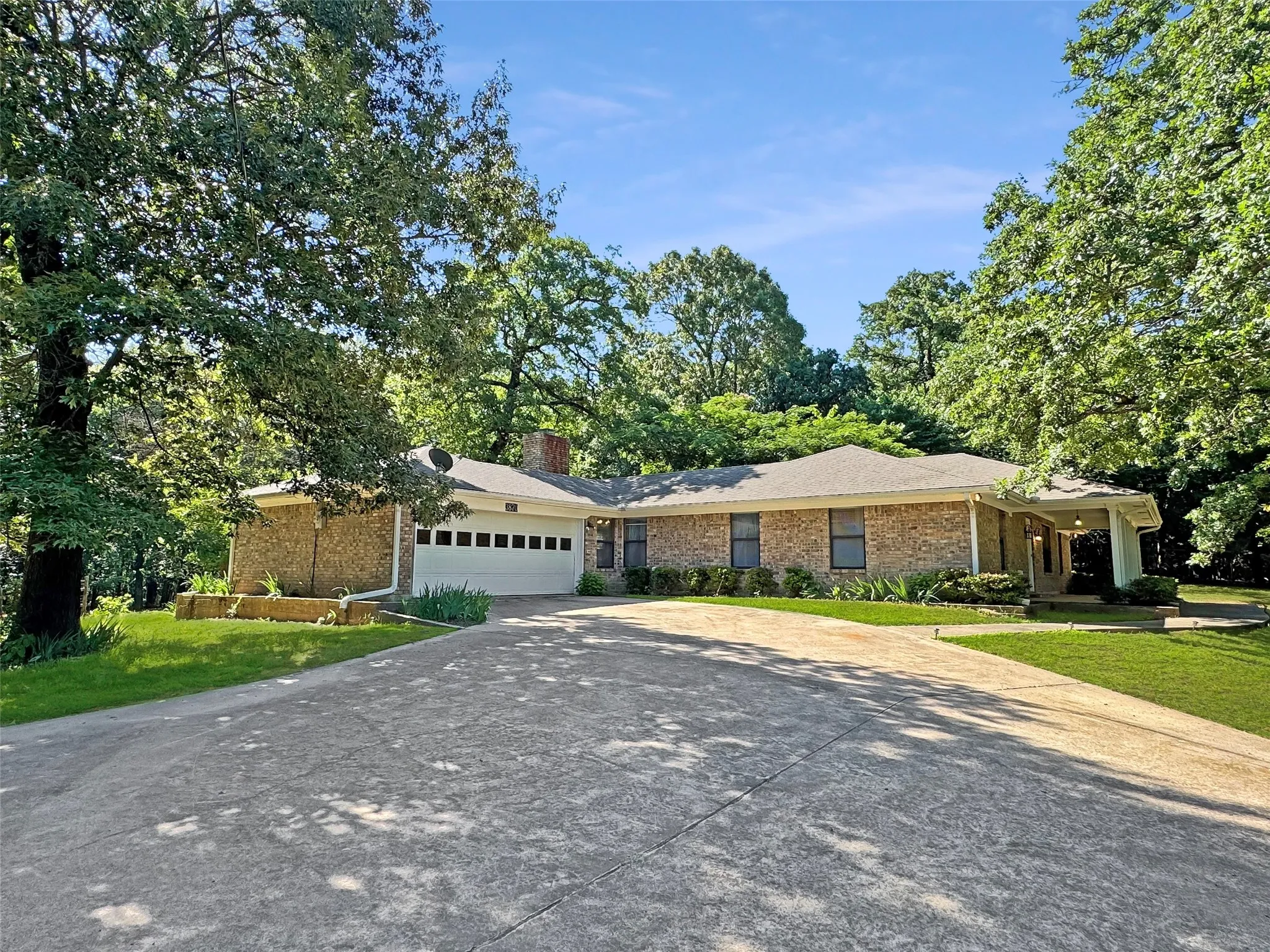 Brick exterior with a covered entry, attached two-car garage, and a concrete driveway