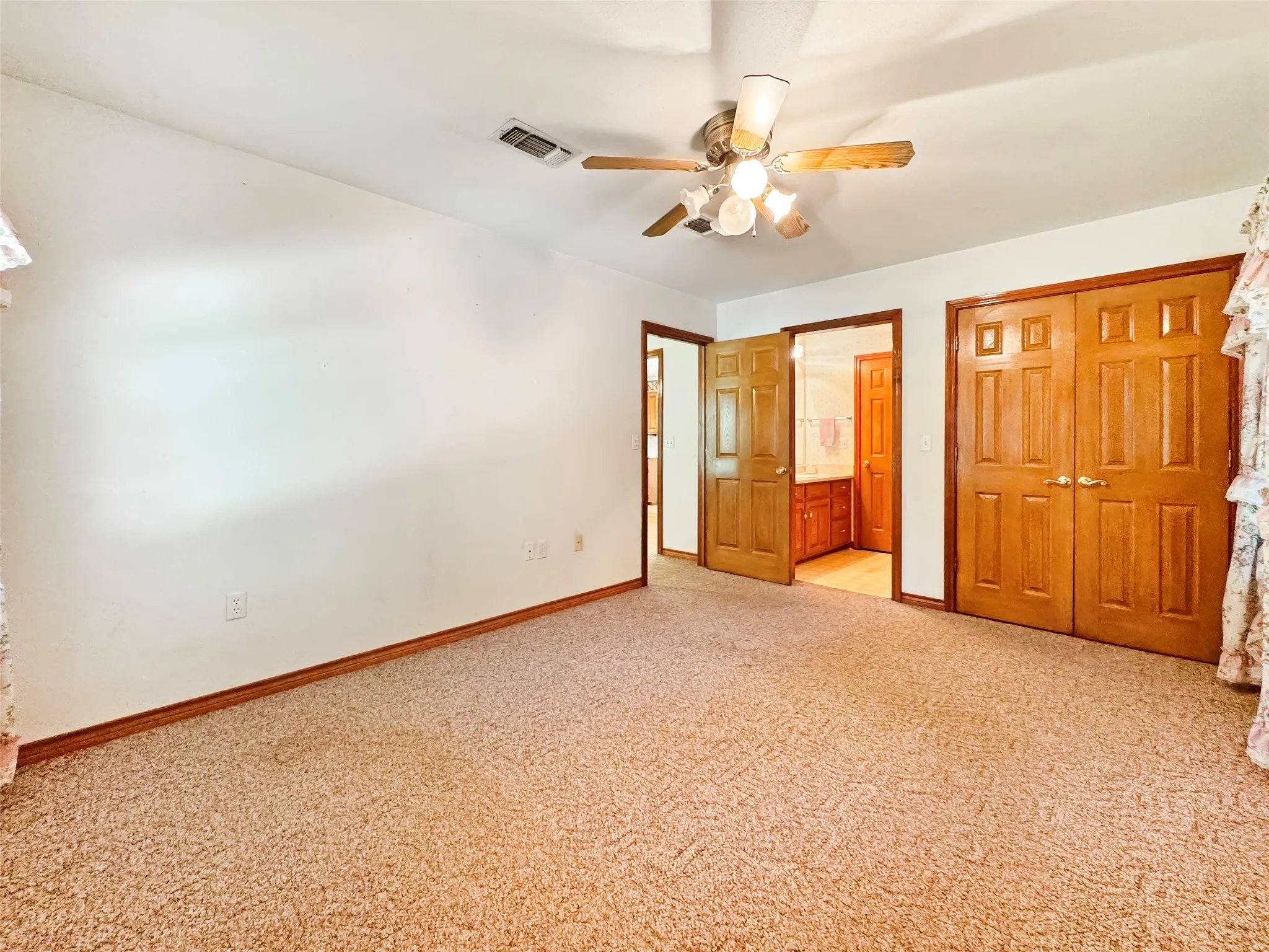 Carpeted room with white walls, wood trim, and a ceiling fan with light fixture