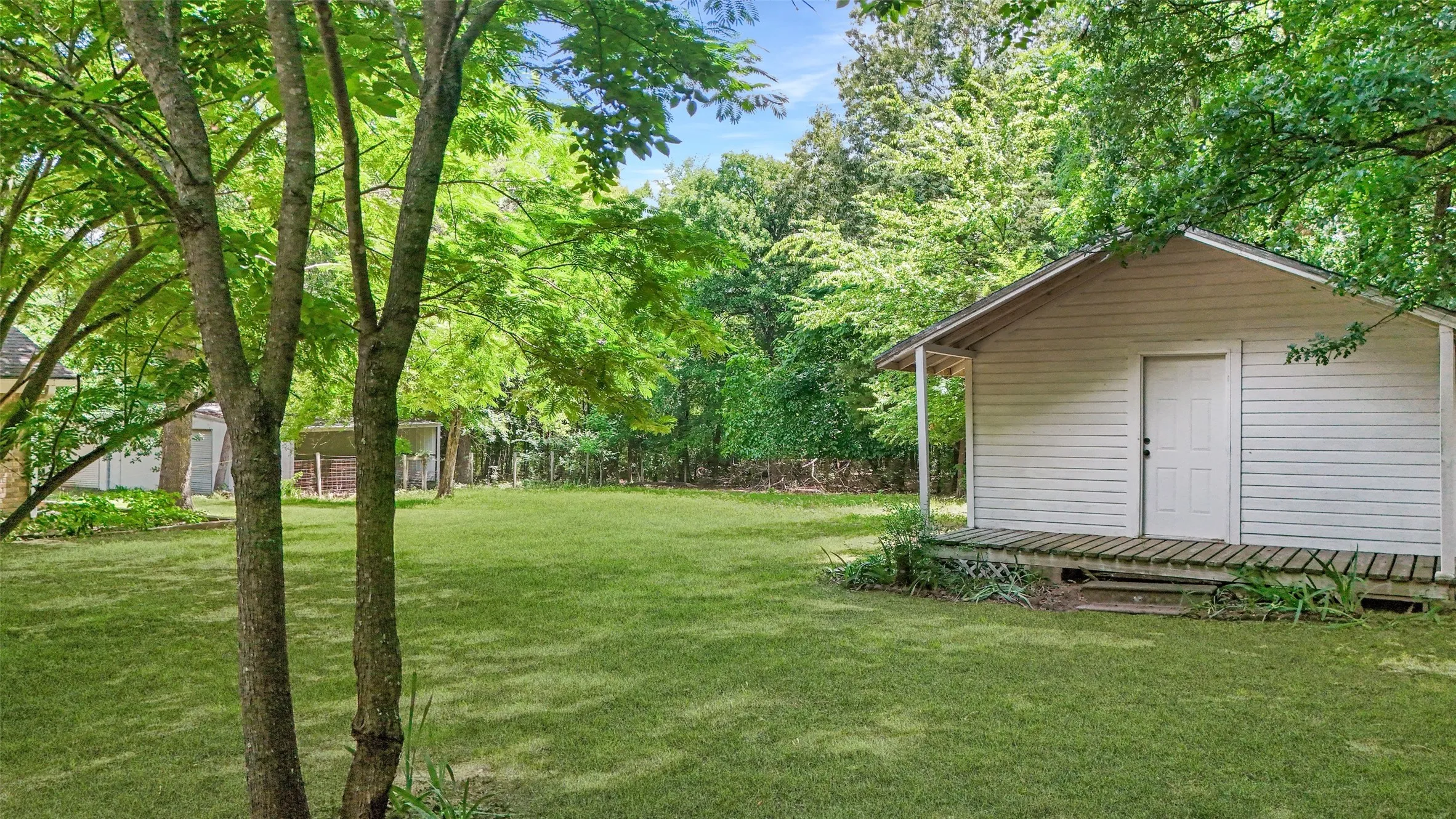 Expansive green lawn featuring a separate ADU with a covered porch and white siding