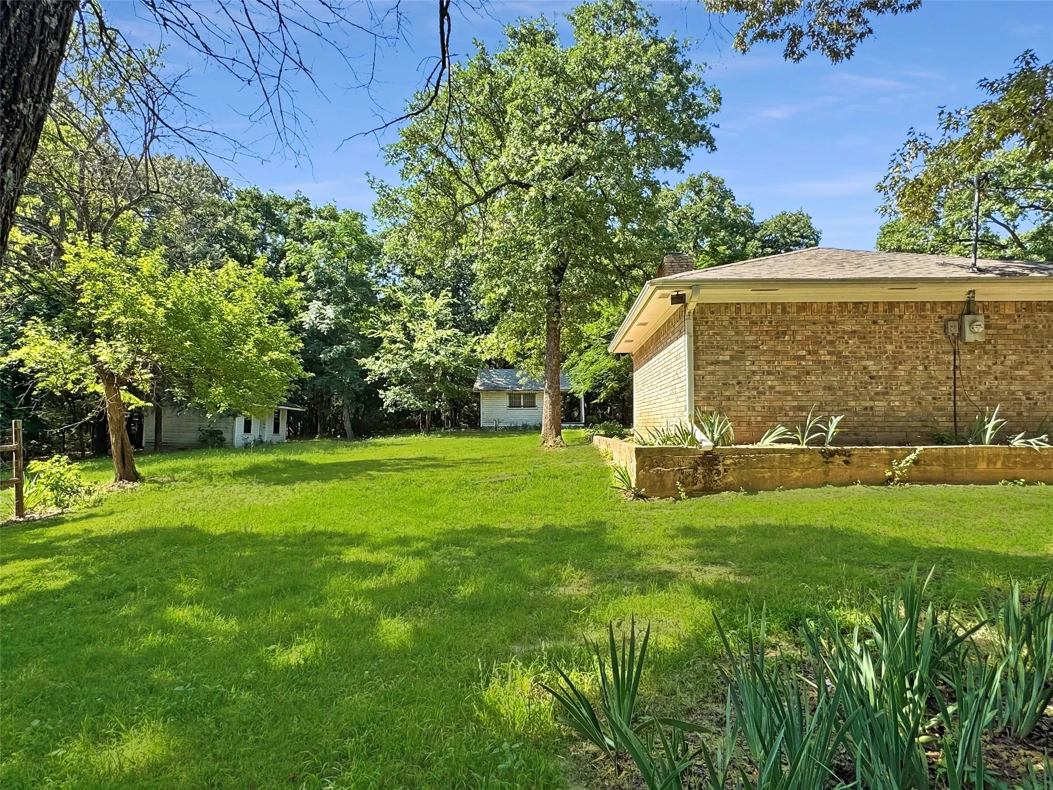 Expansive green lawn with mature trees and a brick-sided exterior