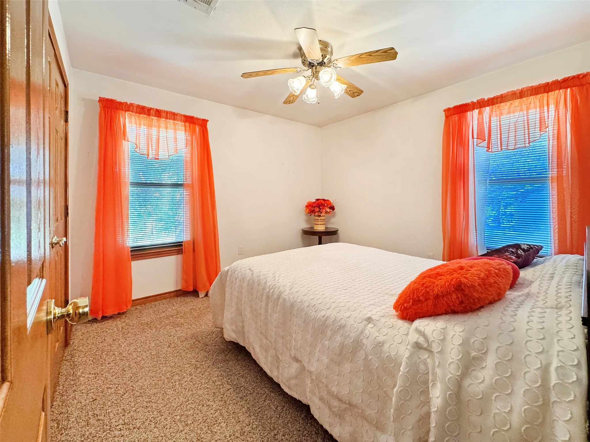 Carpeted room with white walls, two windows featuring horizontal blinds, and a built-in ceiling fan with light fixture