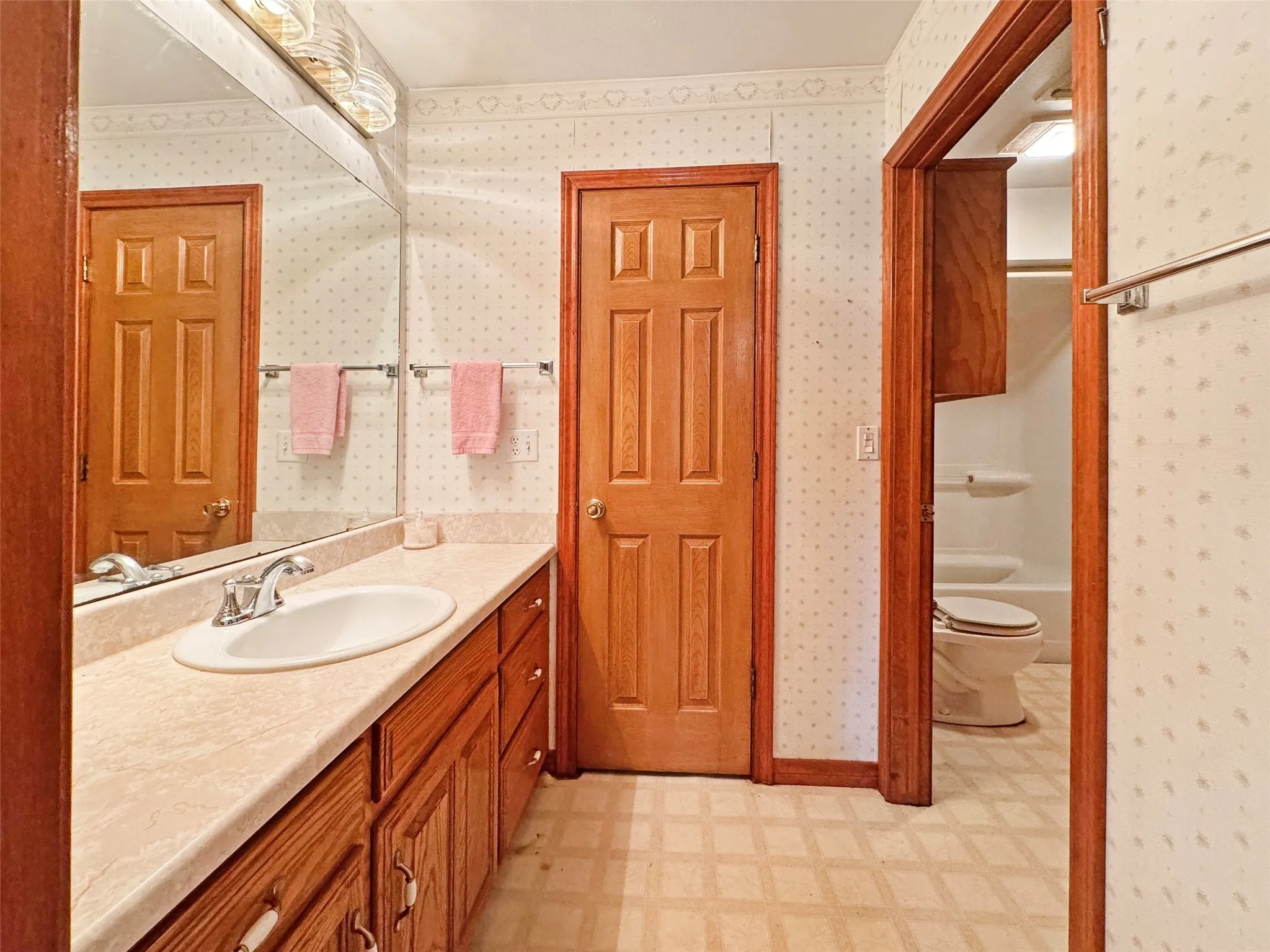 Bathroom vanity featuring a single basin, laminate countertop, and wood-finish cabinetry