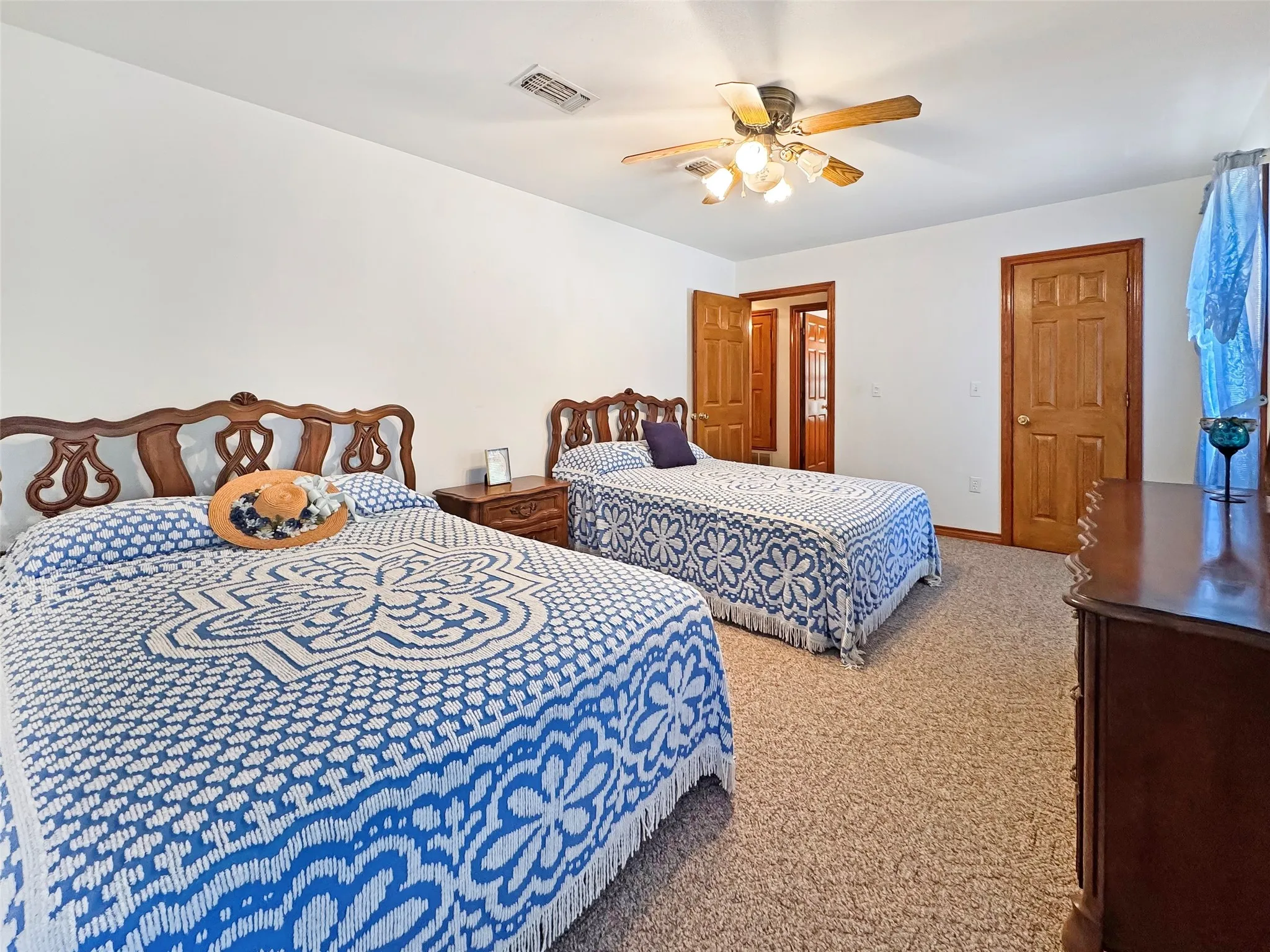 Carpeted bedroom featuring white walls, a ceiling fan with integrated lighting, and wood-paneled doors with matching trim
