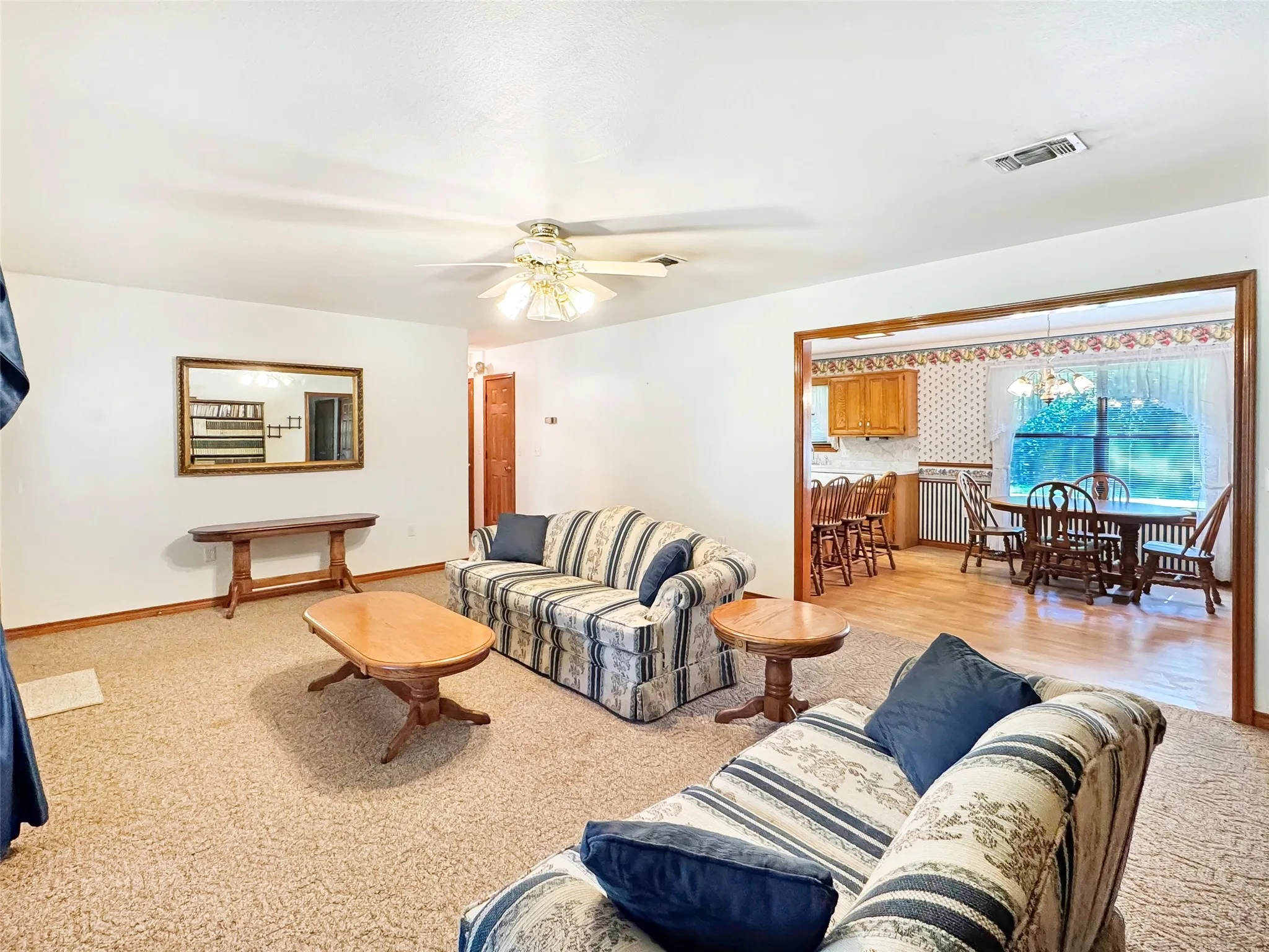 Spacious living area featuring carpet flooring and a ceiling fan