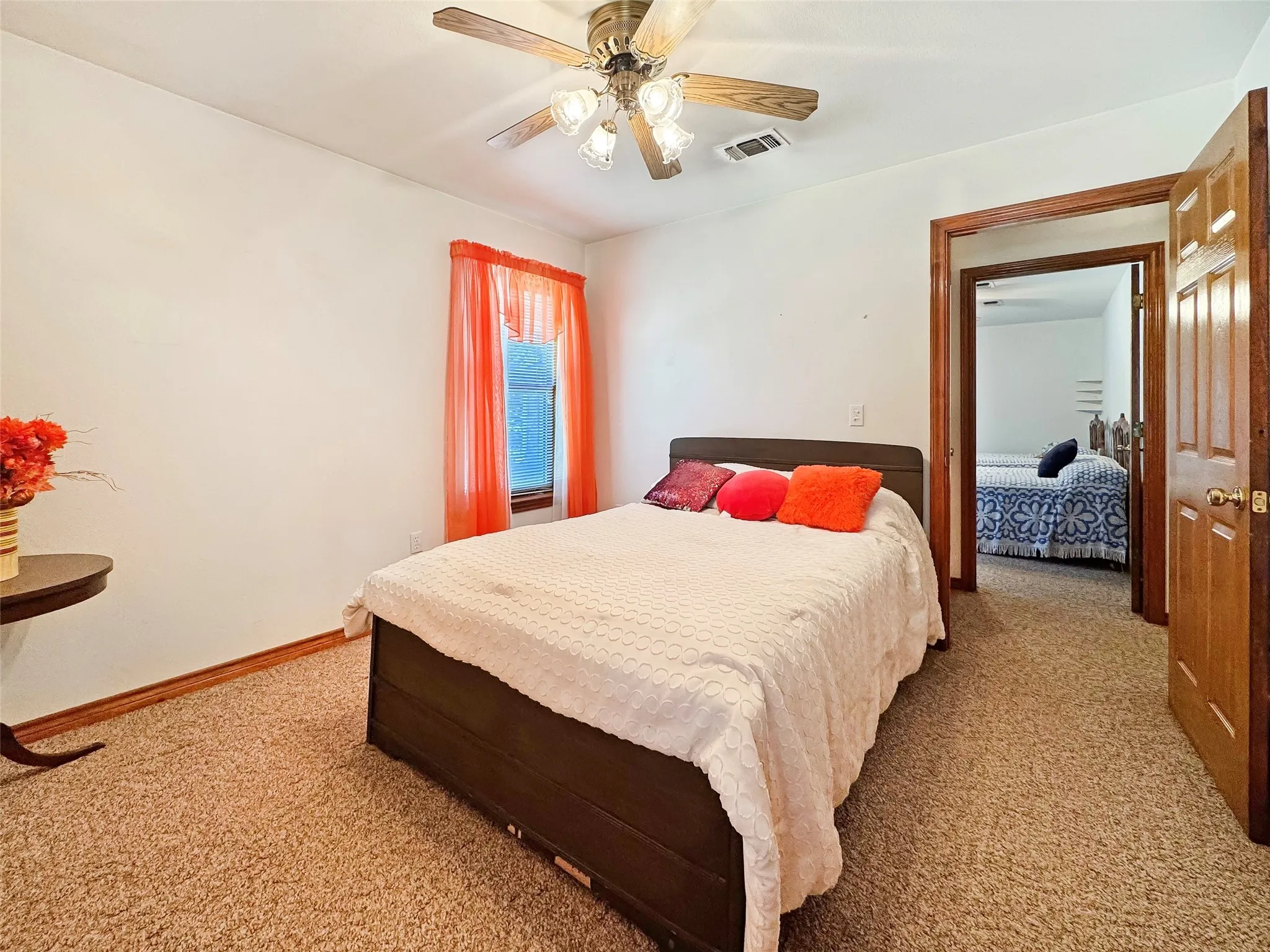Carpeted room featuring a ceiling fan with integrated lighting, a window with trim, and a wood-finish door frame