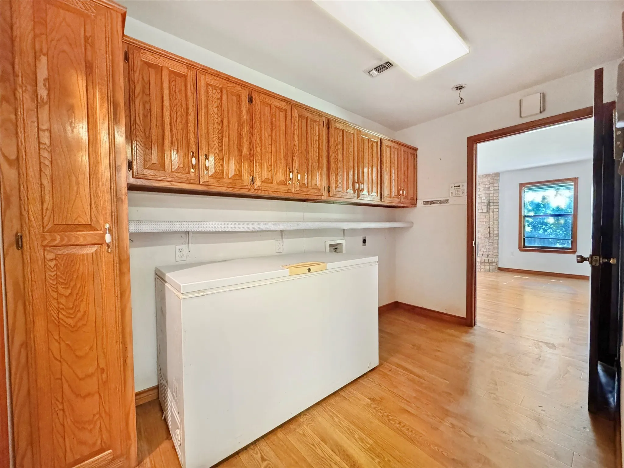 Utility room featuring wood-finish flooring, ample cabinetry, and a dedicated pantry unit