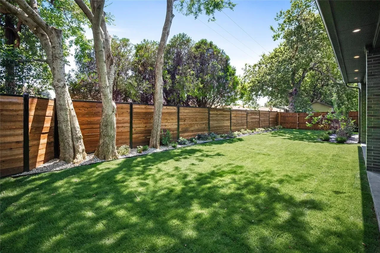 Expansive lawn surrounded by a modern wood-panel fence with dark posts