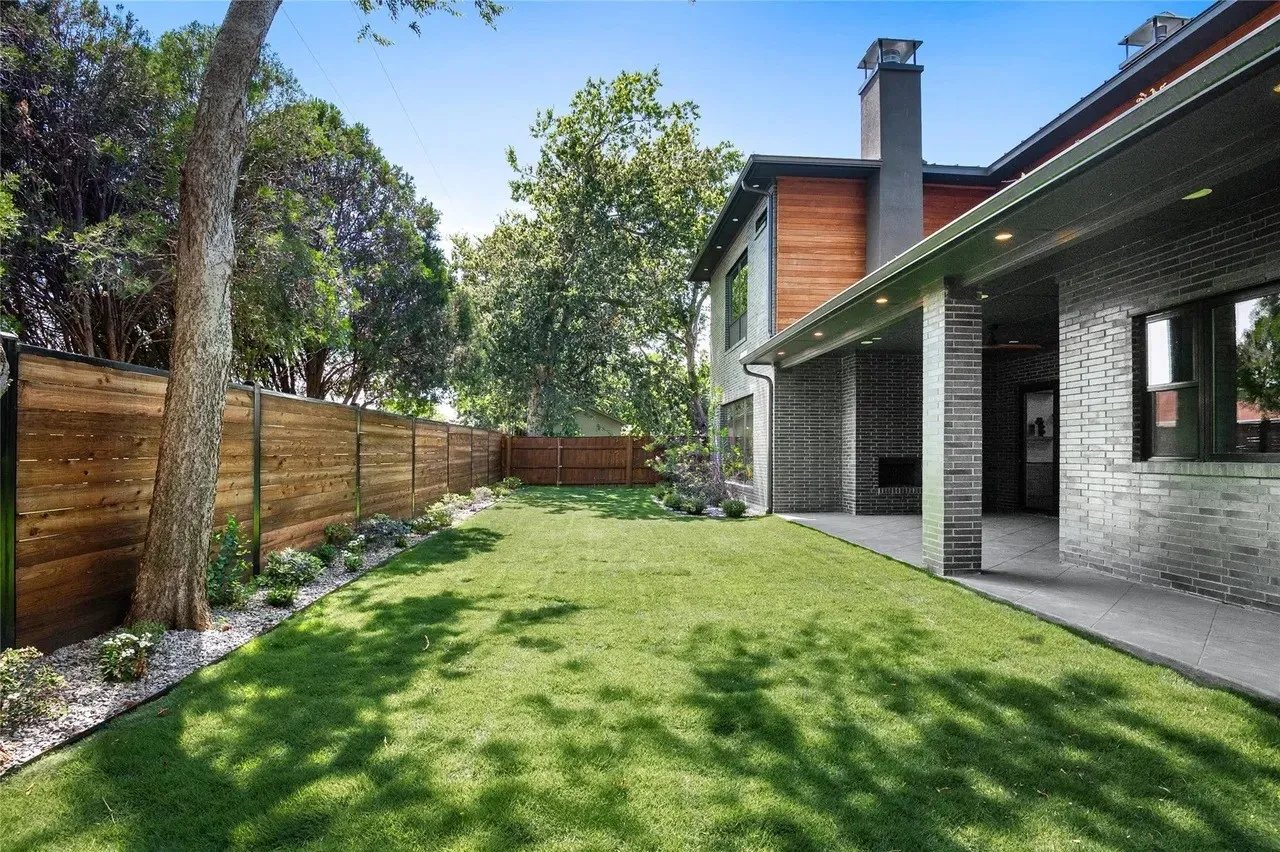 Expansive lawn bordered by a wood privacy fence and mature trees