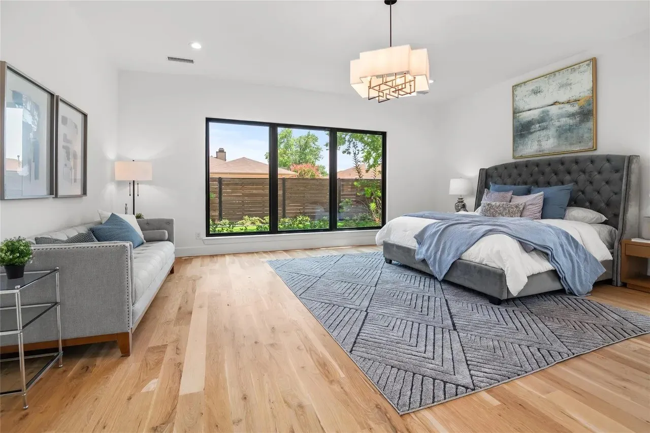 Spacious room featuring light wood-finish flooring, a large multi-pane window with black framing, recessed lighting, and a contemporary ceiling fixture