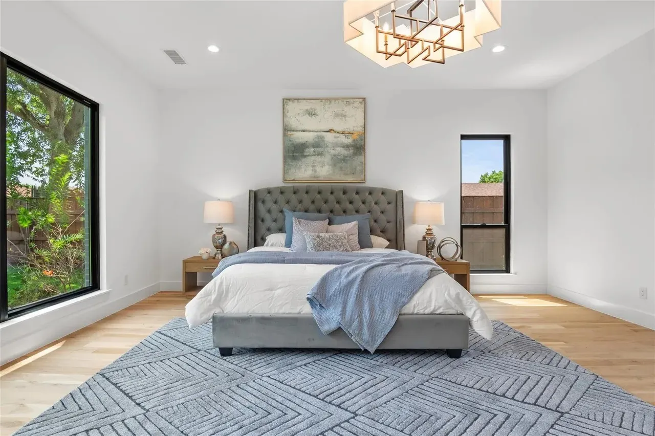 Light wood-finish flooring complements the white walls and modern chandelier