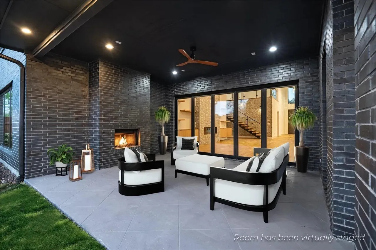 Covered outdoor patio featuring a gray brick fireplace, recessed lighting, and a ceiling fan