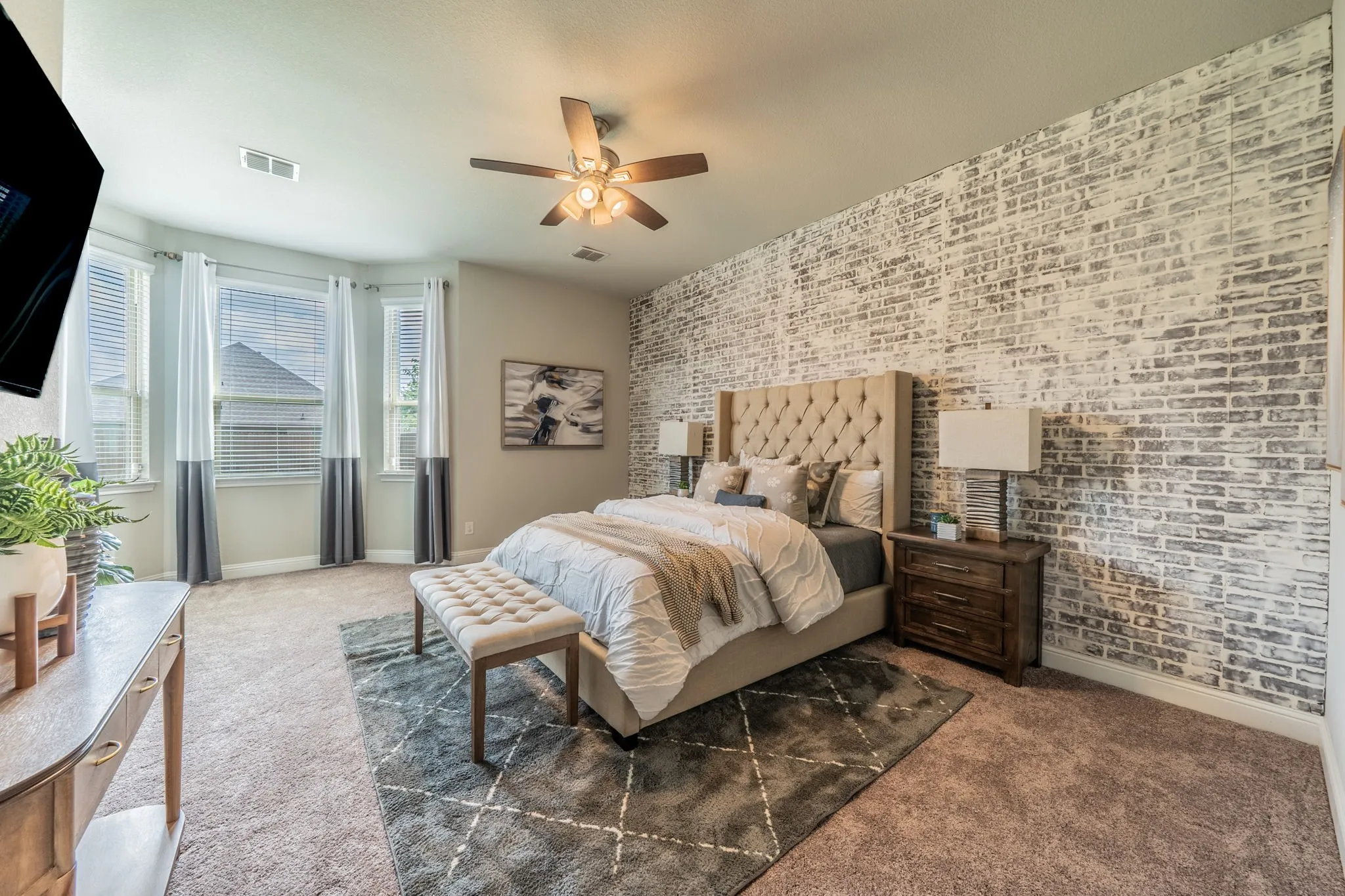 The spacious primary suite features a brick facade, tall windows, and delightful seating area, and a spacious bathroom with walk-in closet.