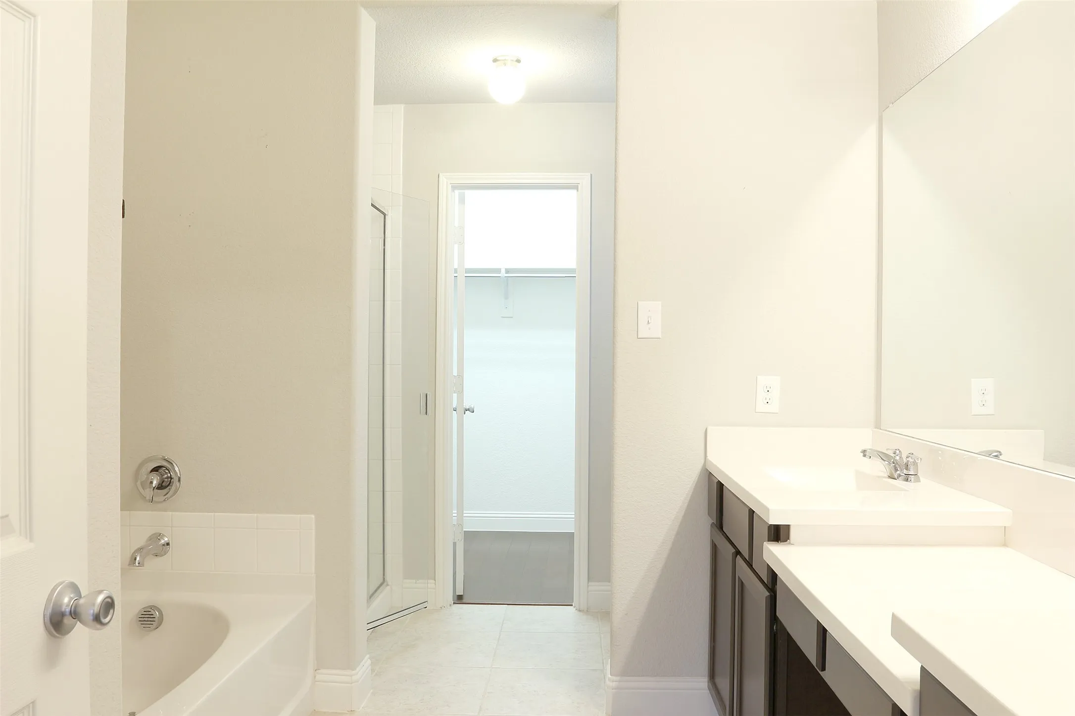 Bathroom featuring a dual vanity with white countertops, dark wood cabinetry, and chrome fixtures