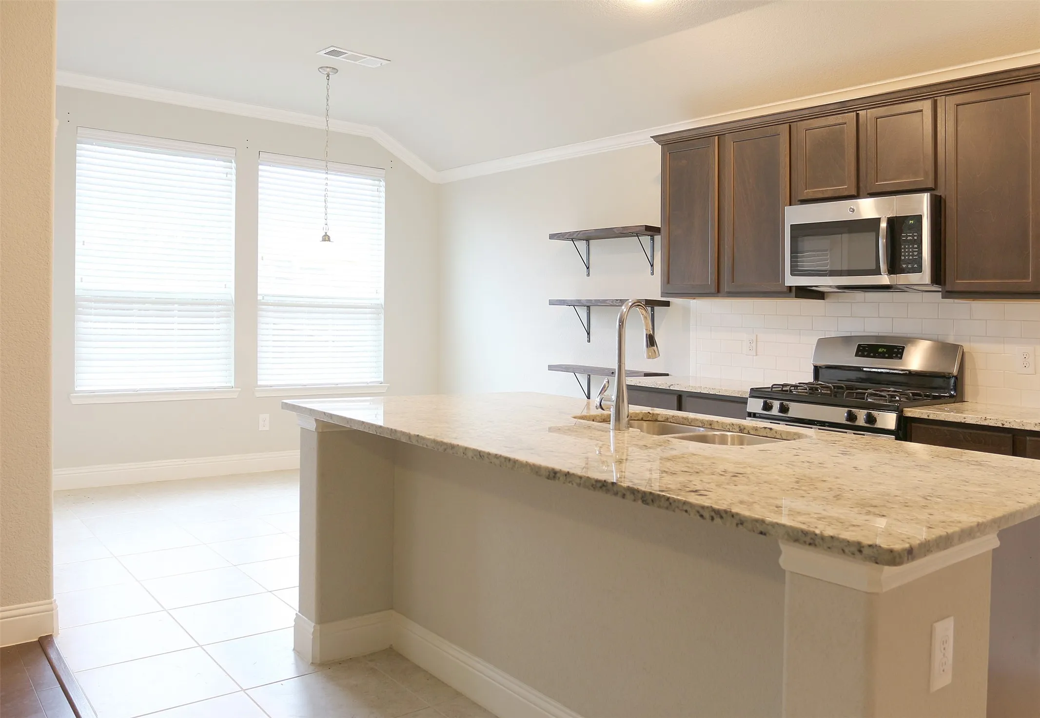 Kitchen featuring a large island with a stone countertop and double basin sink