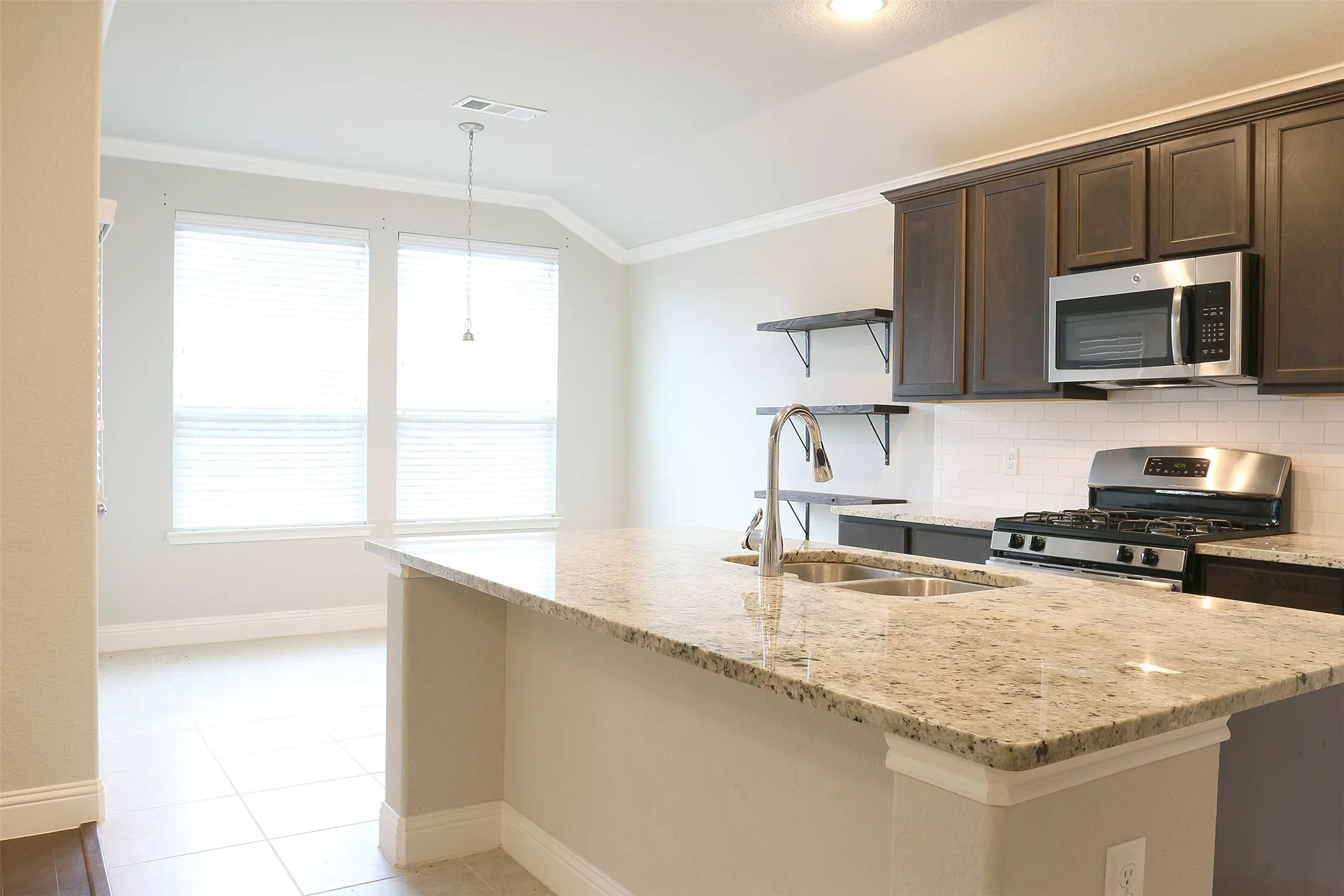 Kitchen featuring an island with stone countertops and a double-basin stainless steel sink