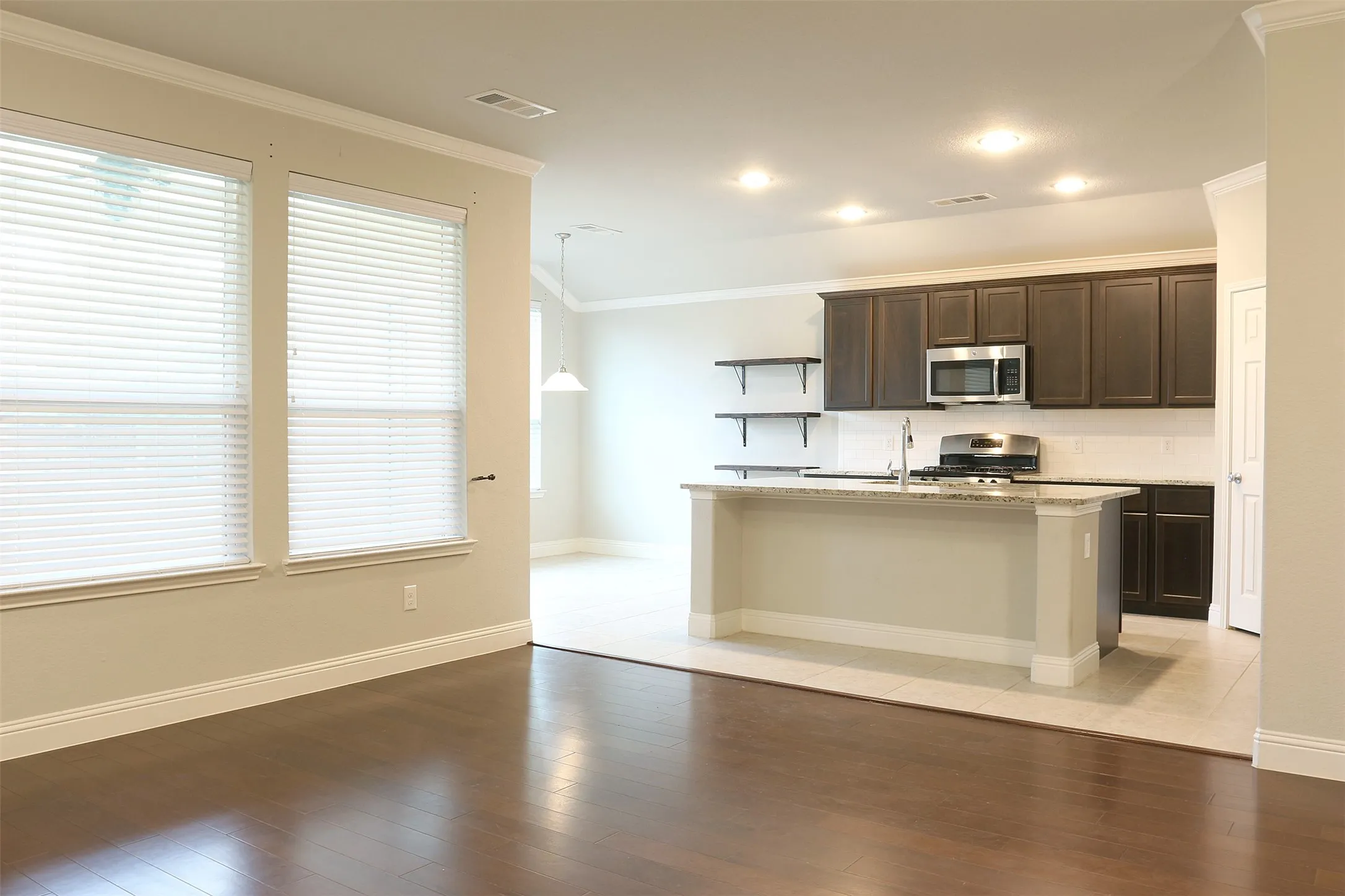 Open-concept kitchen featuring dark wood cabinetry, stainless steel appliances, a center island with bar seating, and recessed lighting