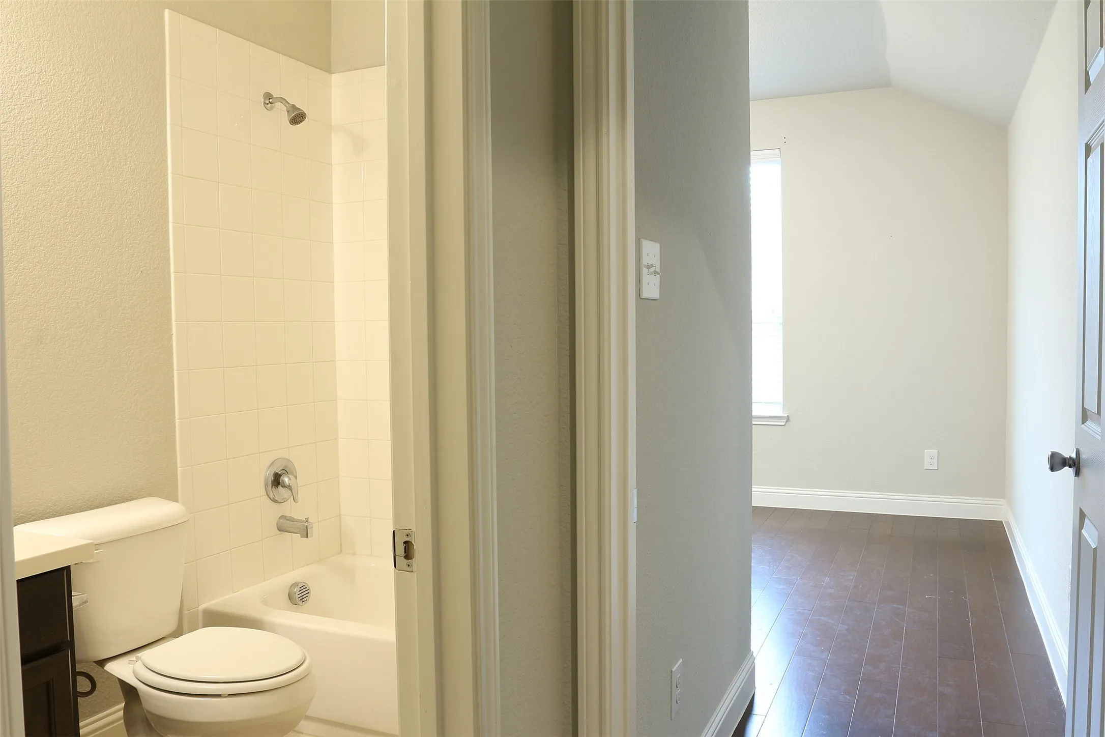 Full bathroom featuring a tub/shower combination with white tile surround, a toilet, and a dark wood-finish vanity