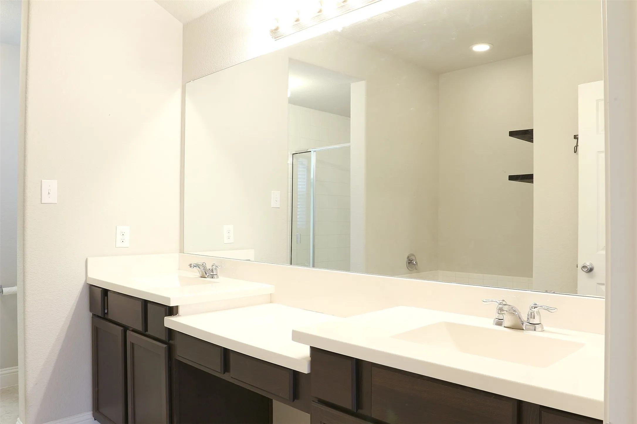 Dual vanity with integrated sinks, white countertops, dark wood-finish cabinetry, and chrome fixtures