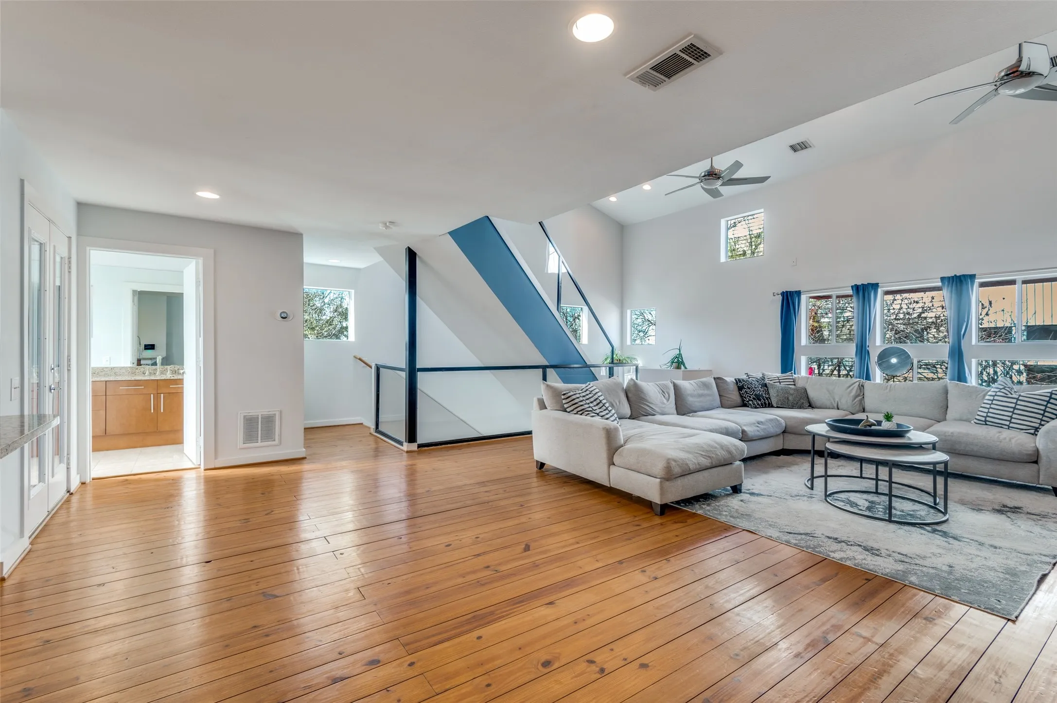 Light filled second floor living area with vaulted ceilings and oversized windows