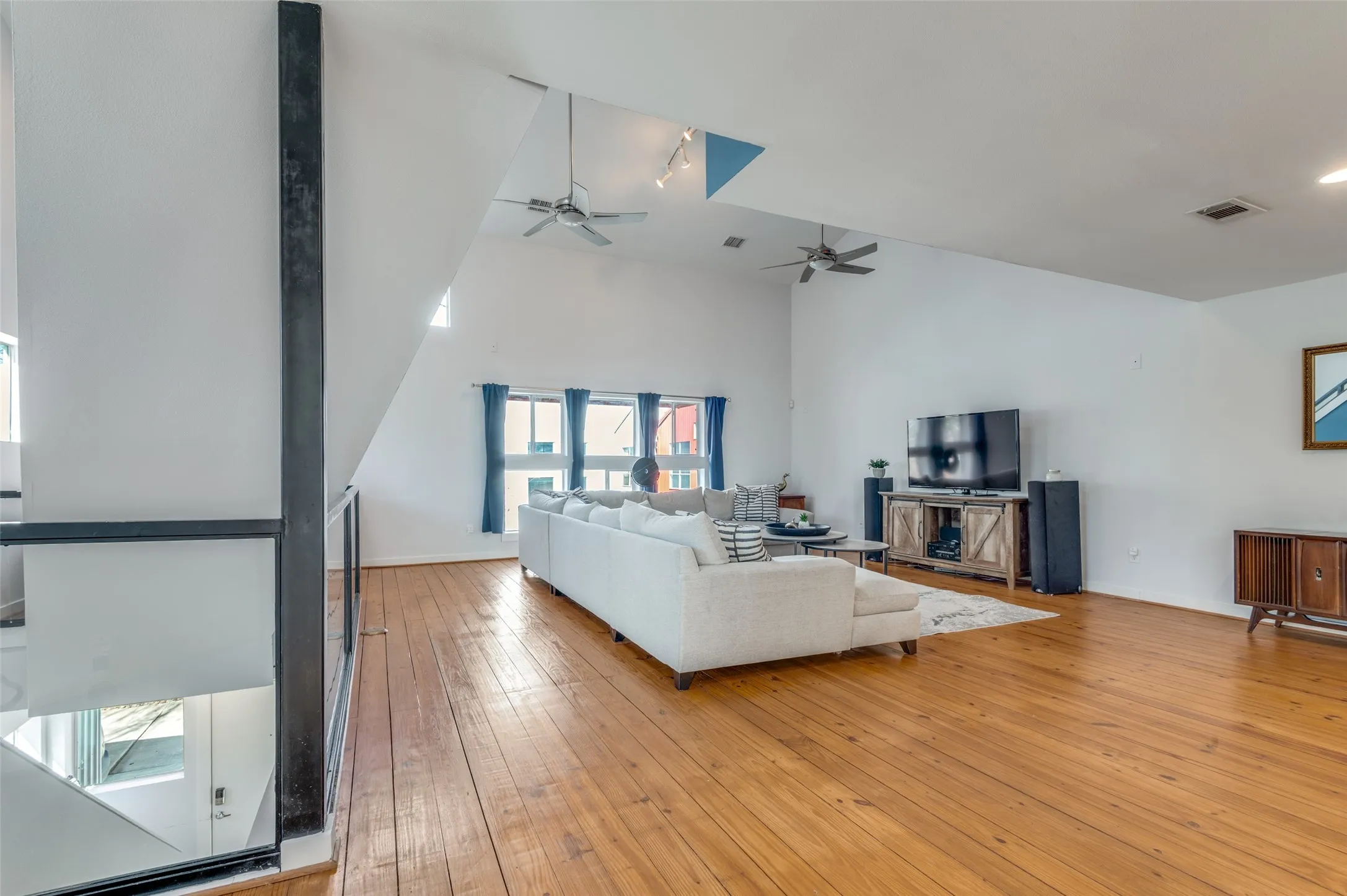 Light filled second floor living area with vaulted ceilings and oversized windows