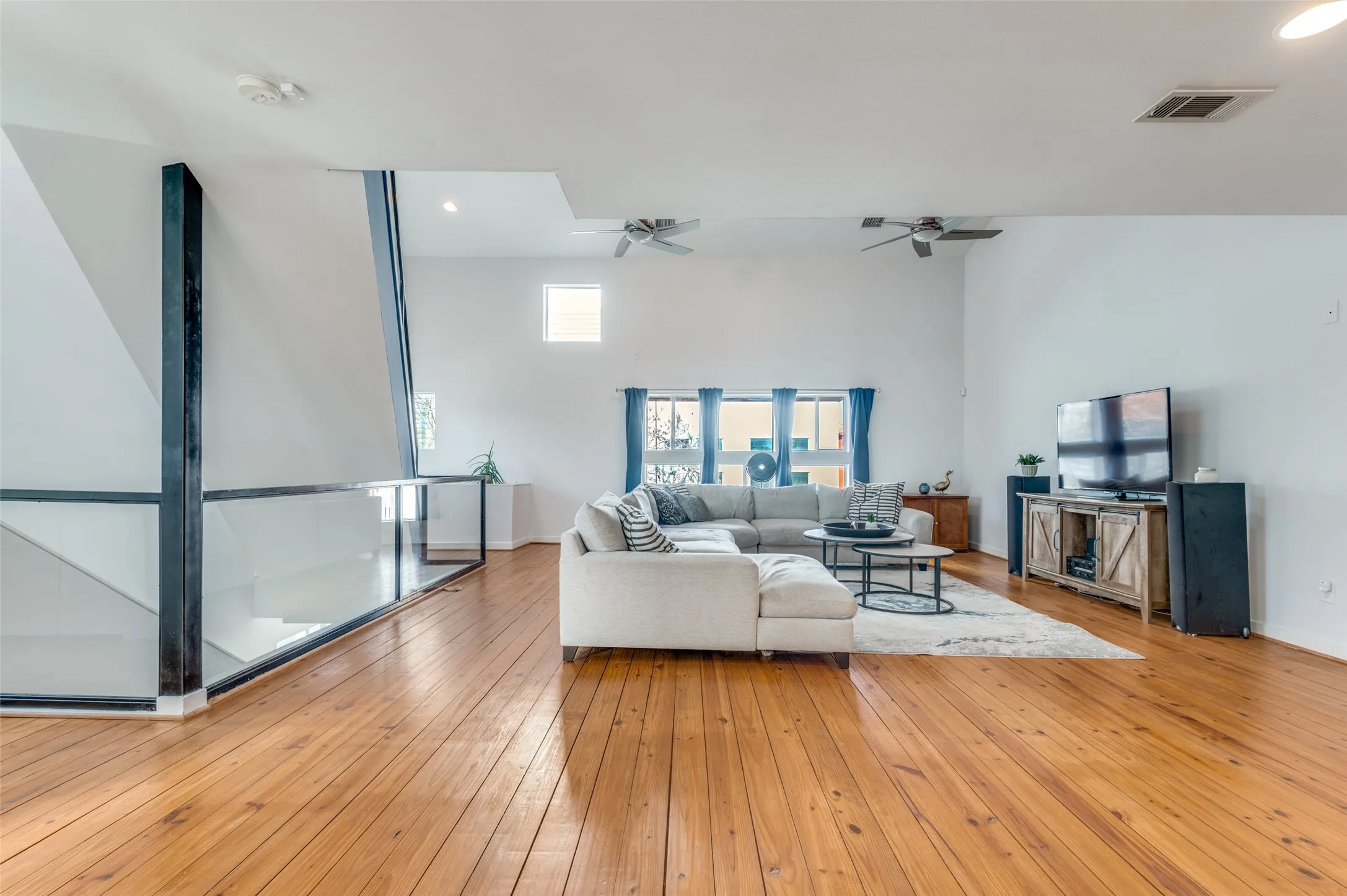 Light filled second floor living area with vaulted ceilings and oversized windows