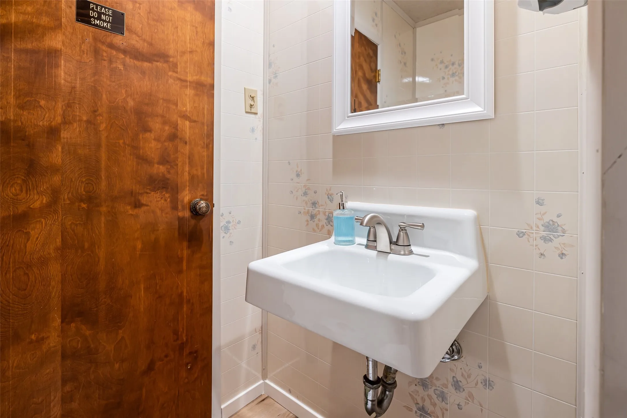 White wall-mounted sink with a polished chrome faucet set against tiled walls