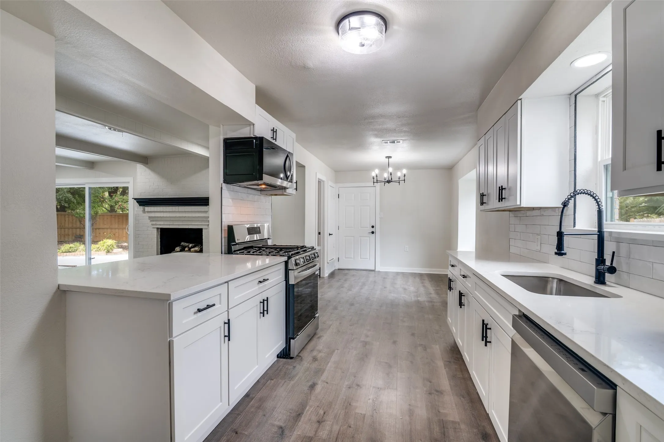 Modern kitchen featuring white shaker cabinetry, stainless steel appliances, light countertops, and wood-finish flooring