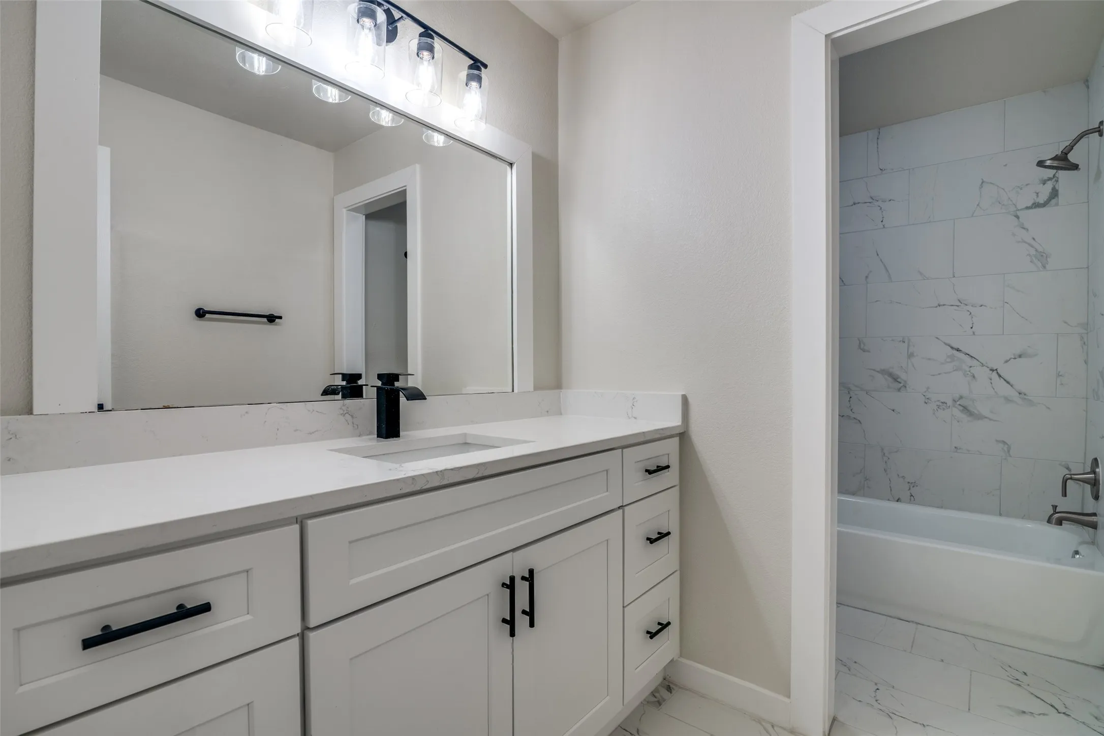 Bathroom featuring a white vanity with slab countertop, undermount sink, and matte black faucet