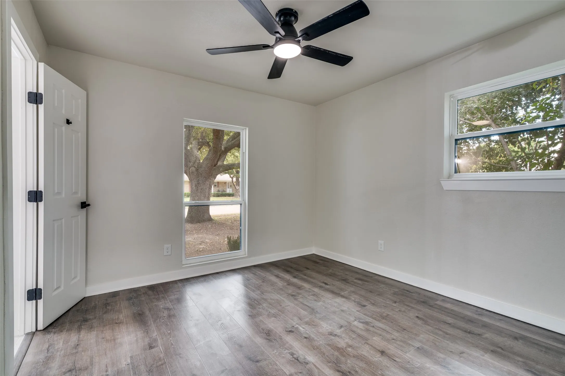 Interior room featuring wood-finish flooring, light neutral wall paint, and white trim