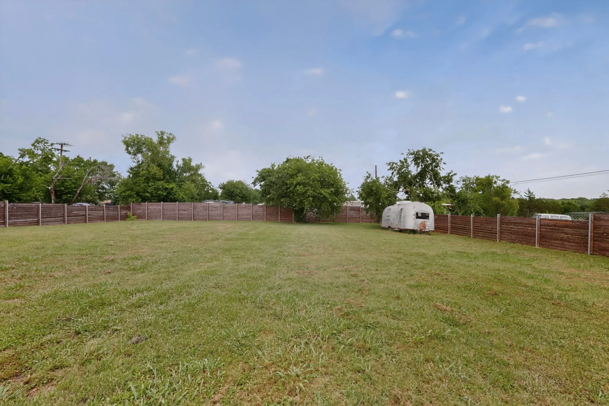 Expansive backyard featuring a gravel patio, stone fire pit, string lighting, and raised garden beds