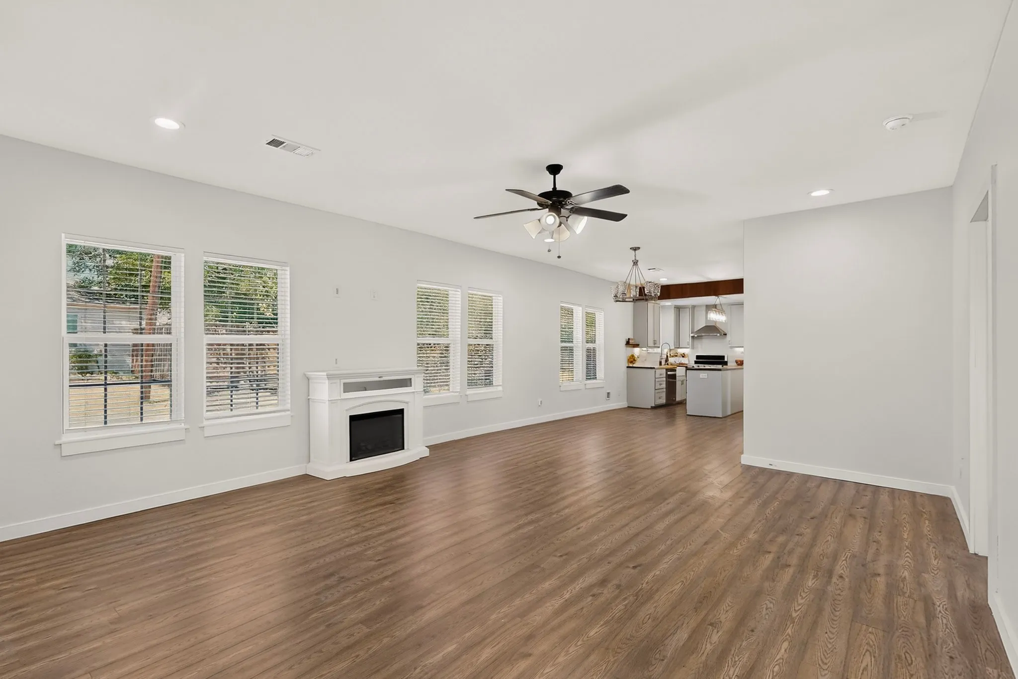 Open-concept living area featuring wood-finish flooring, recessed lighting, and multiple windows
