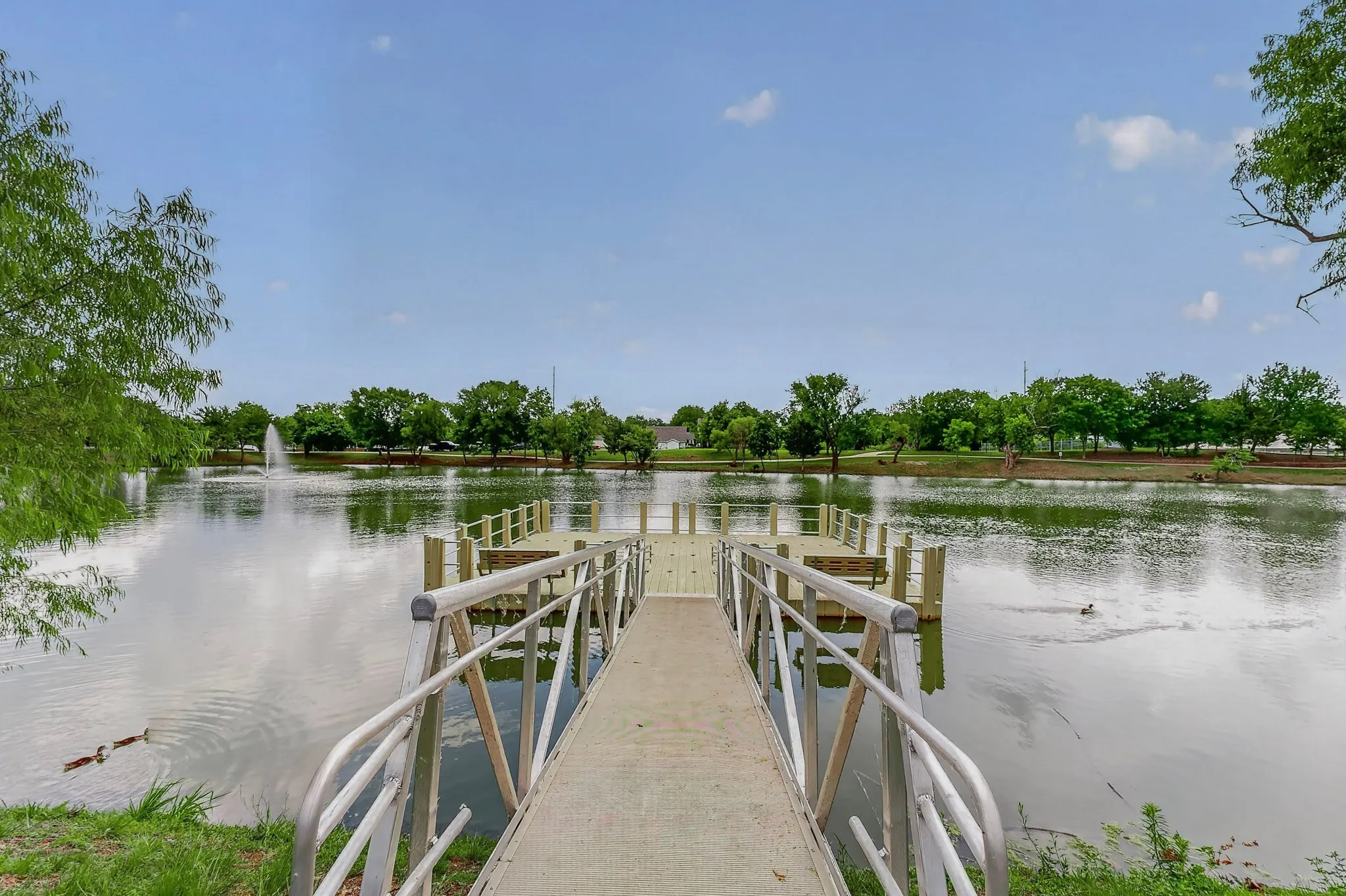 Private dock featuring a concrete ramp and aluminum railings leading to a wooden platform