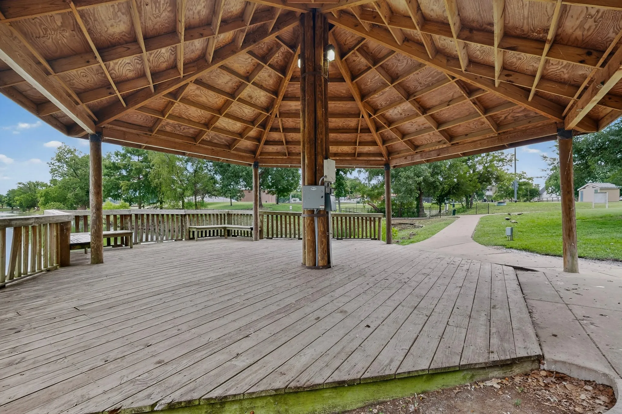 Expansive hexagonal gazebo featuring a wood-finish floor and exposed beam ceiling