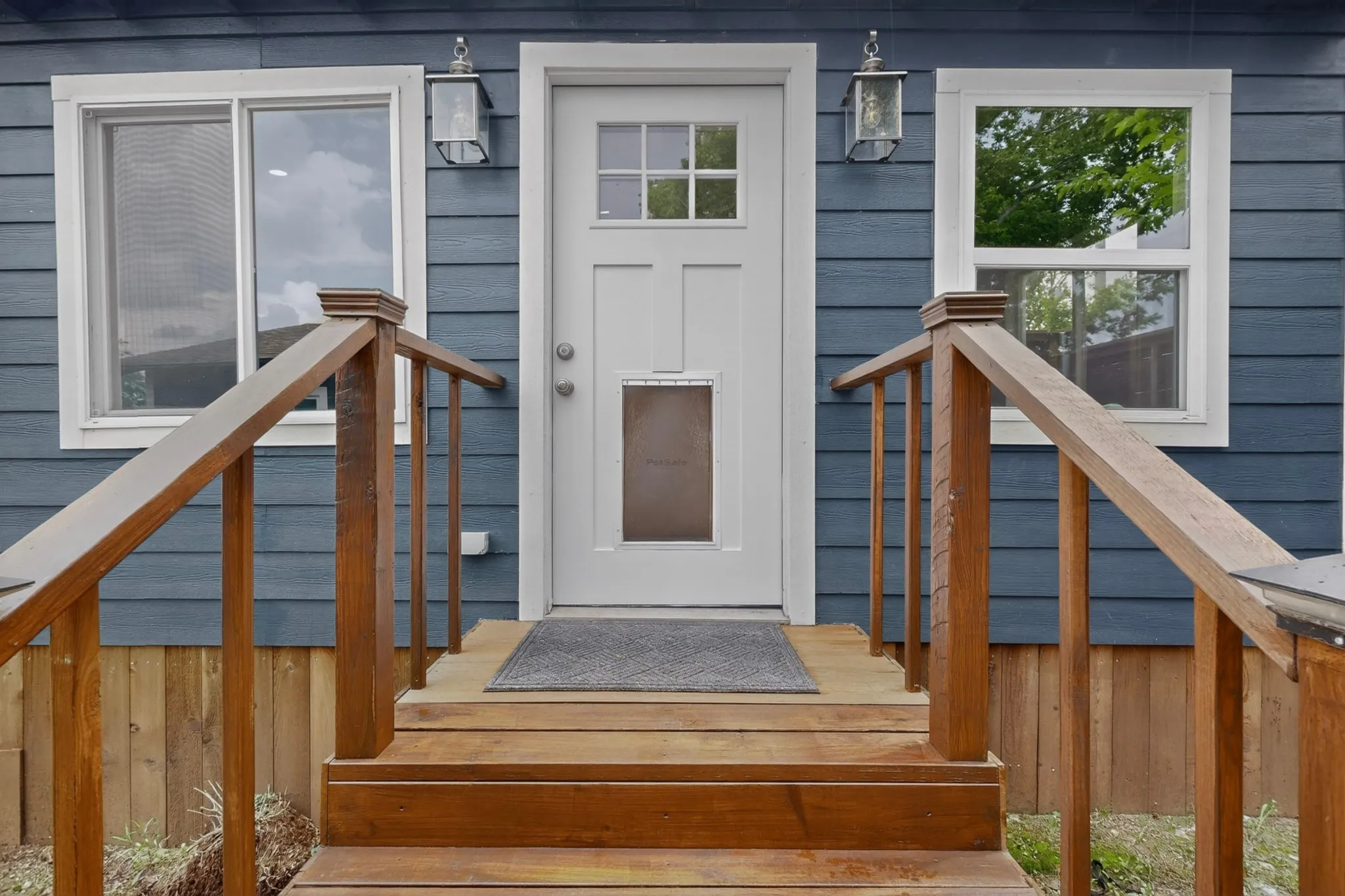 Exterior building featuring horizontal siding in a dark blue finish, a white paneled door with glass inserts, and a single-pane window