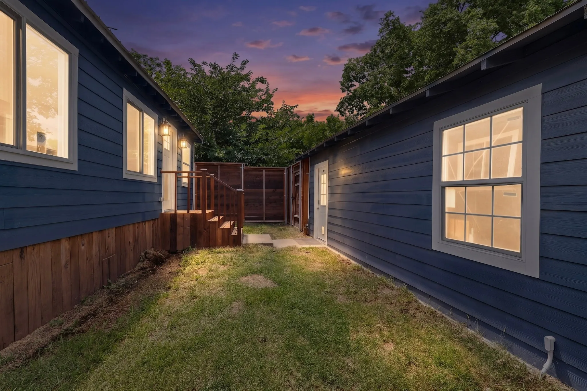 Expansive backyard featuring a gravel patio with a built-in fire pit, multiple raised metal garden beds, and a detached storage shed