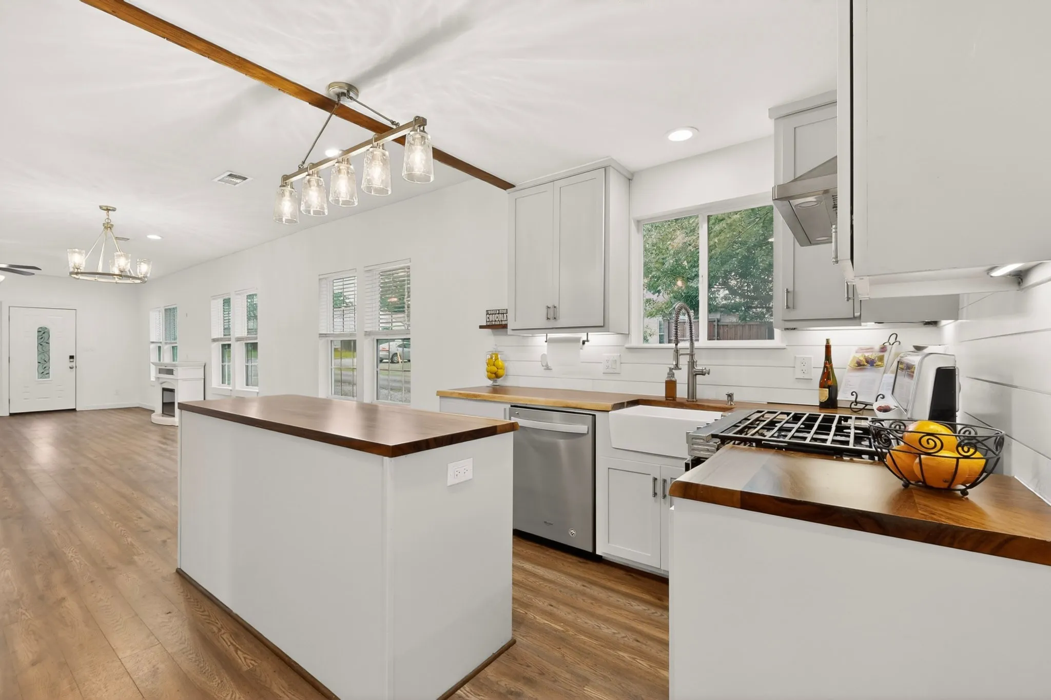 Kitchen island featuring a wood-finish countertop, light gray cabinetry, and a built-in microwave