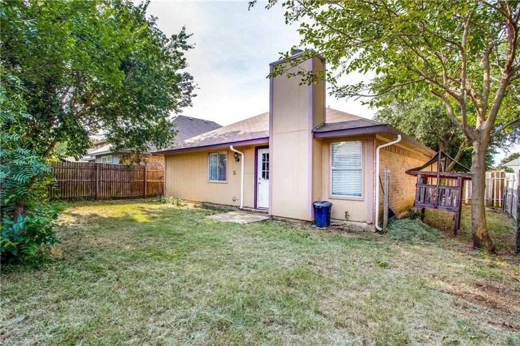 Expansive rear yard featuring mature trees and a wooden privacy fence