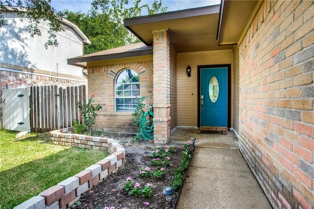 Brick exterior featuring an arched window with white muntins and a blue panel door with an oval glass insert