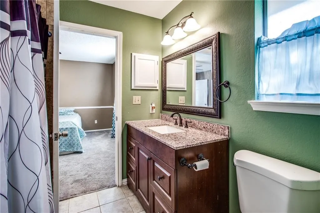 Bathroom featuring a vanity with a granite countertop, undermount sink, and dark wood cabinetry