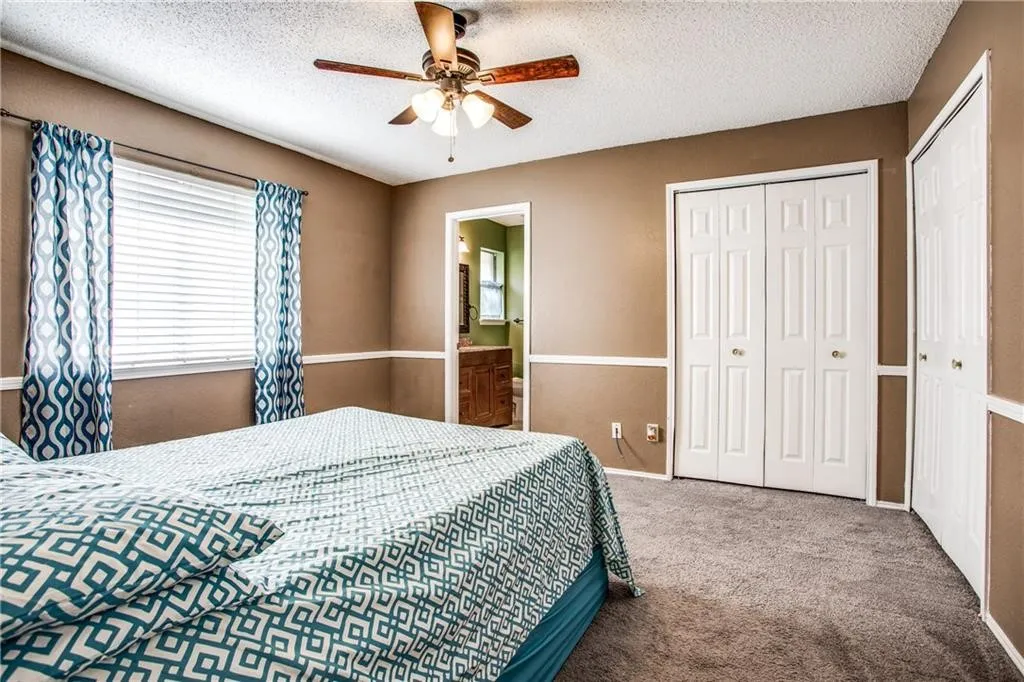Carpeted room featuring a ceiling fan with light fixture, window with blinds, and white bi-fold closet doors