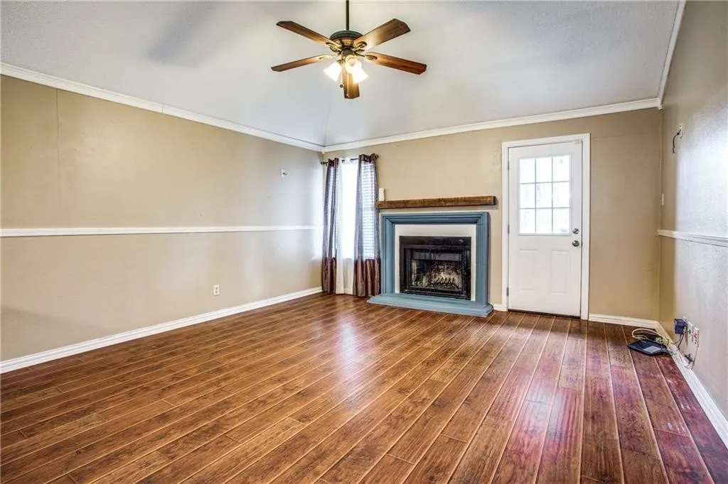 Spacious room featuring wood-finish flooring, a fireplace with a wood mantle, and a ceiling fan