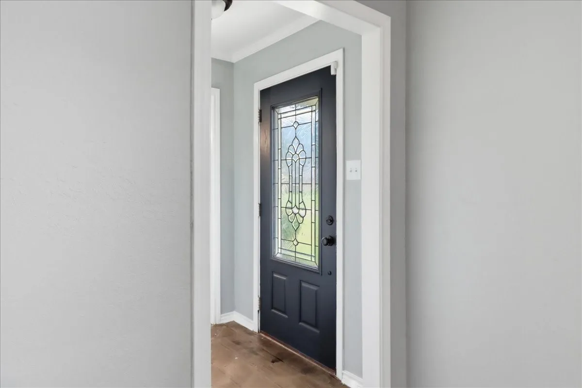 Entryway featuring a dark paneled door with decorative glass, light gray wall finishes, and wood-finish flooring