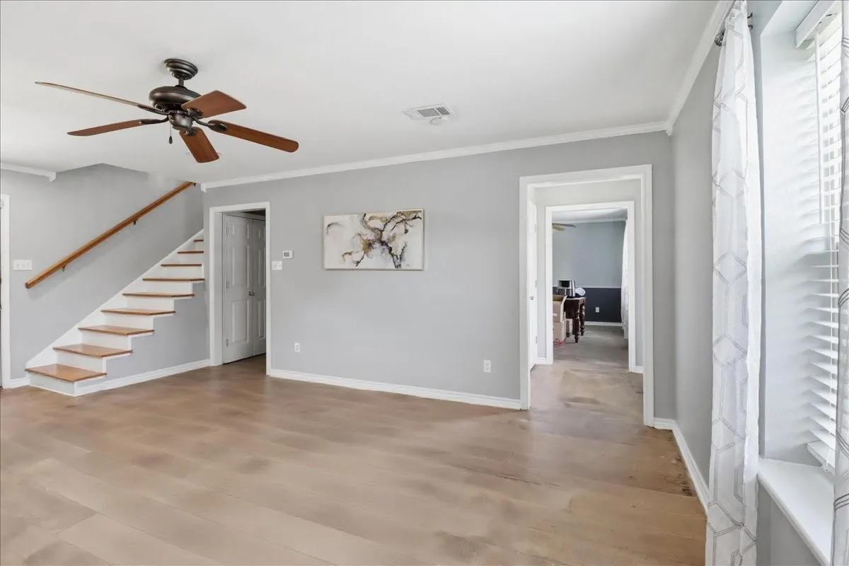 Bright interior space featuring painted concrete flooring, a contemporary ceiling fan, and a staircase with wood treads