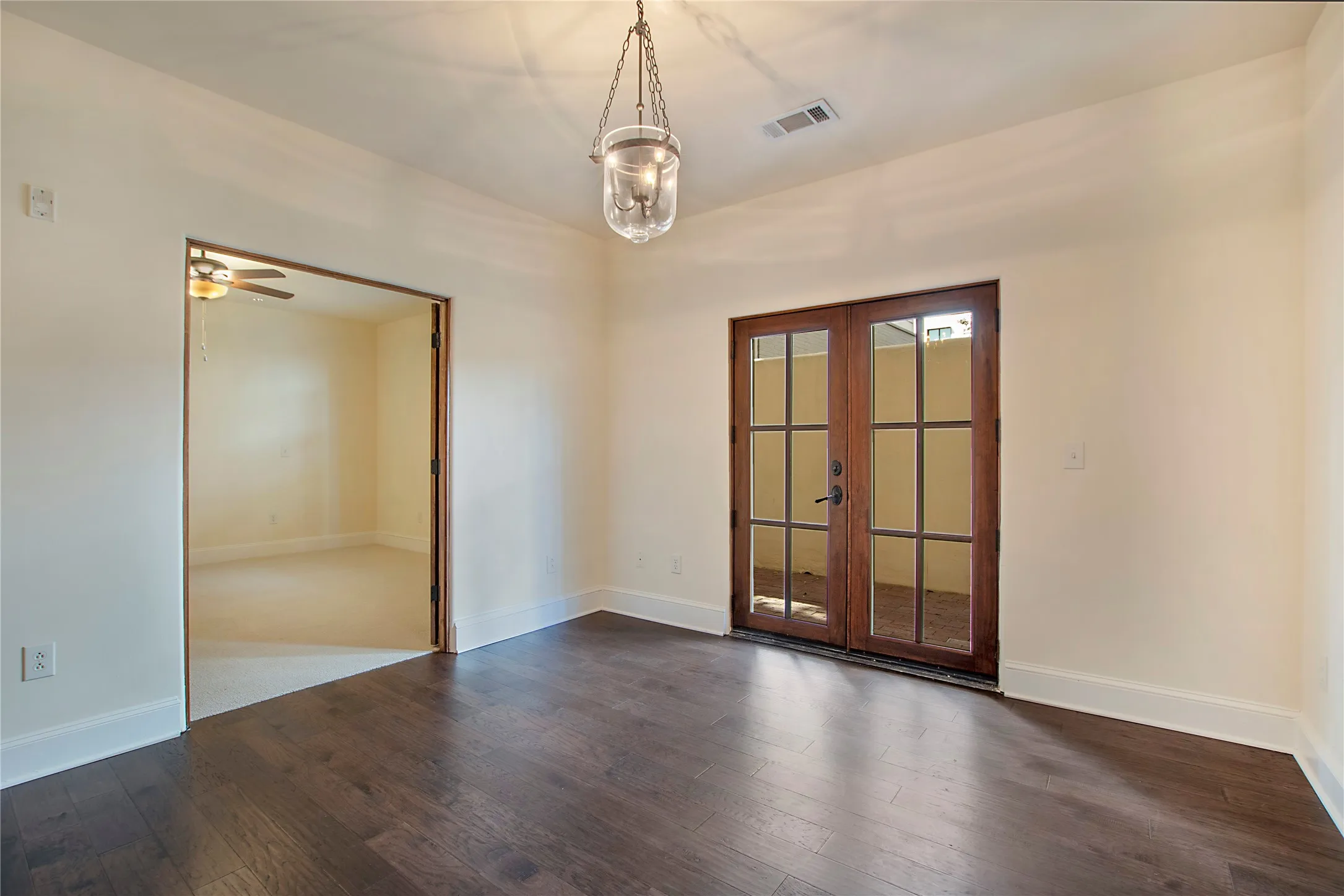 Empty room with ceiling fan, dark hardwood / wood-style floors, and french doors