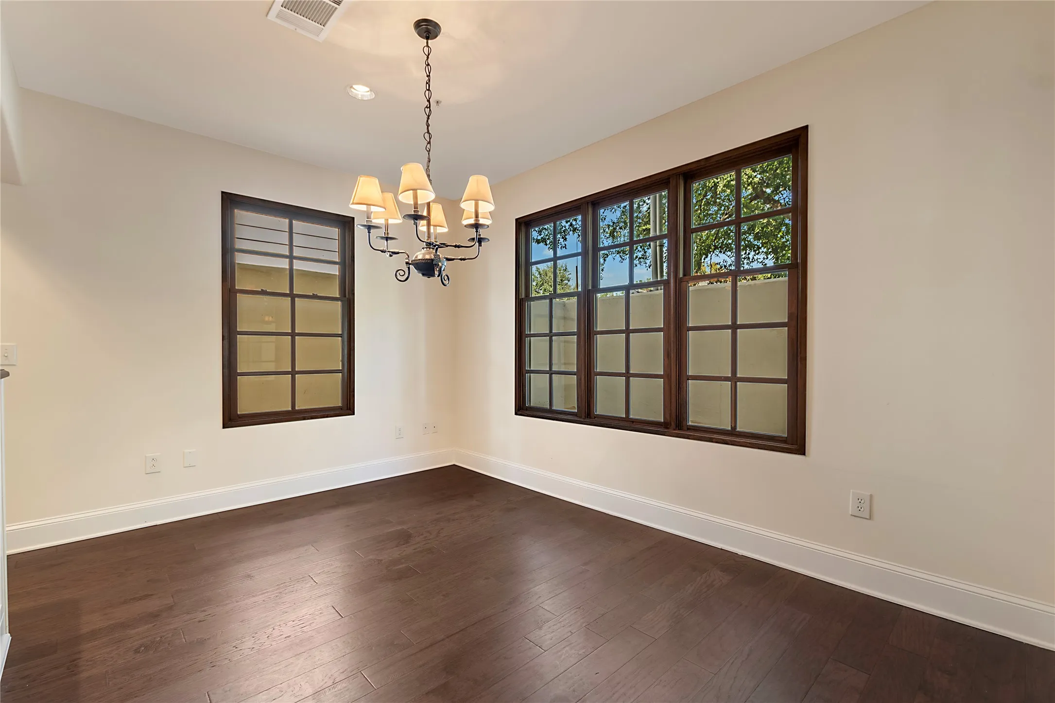 Spare room featuring a notable chandelier and dark hardwood / wood-style flooring