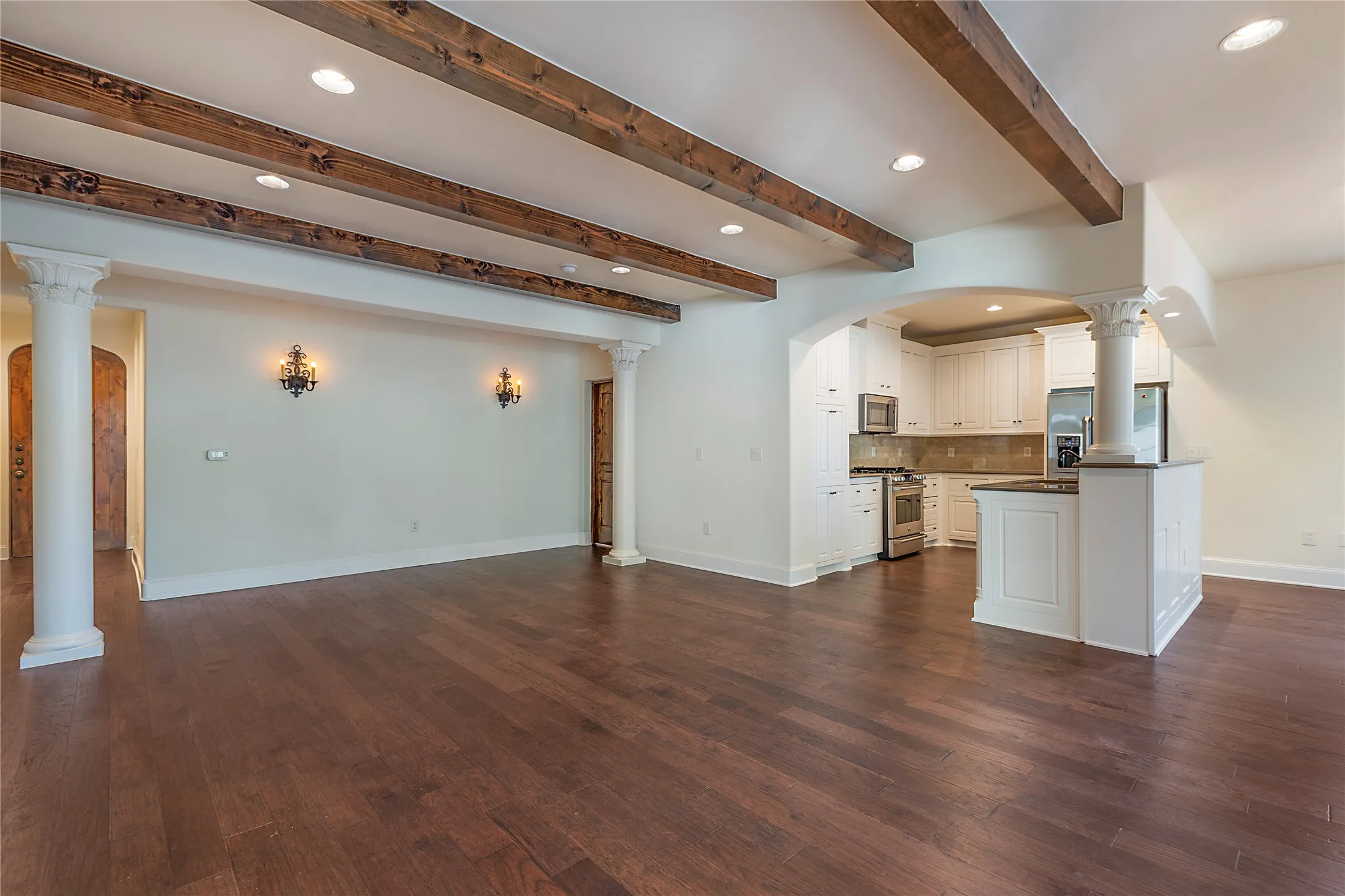 Kitchen featuring appliances with stainless steel finishes, backsplash, dark wood-type flooring, and white cabinetry
