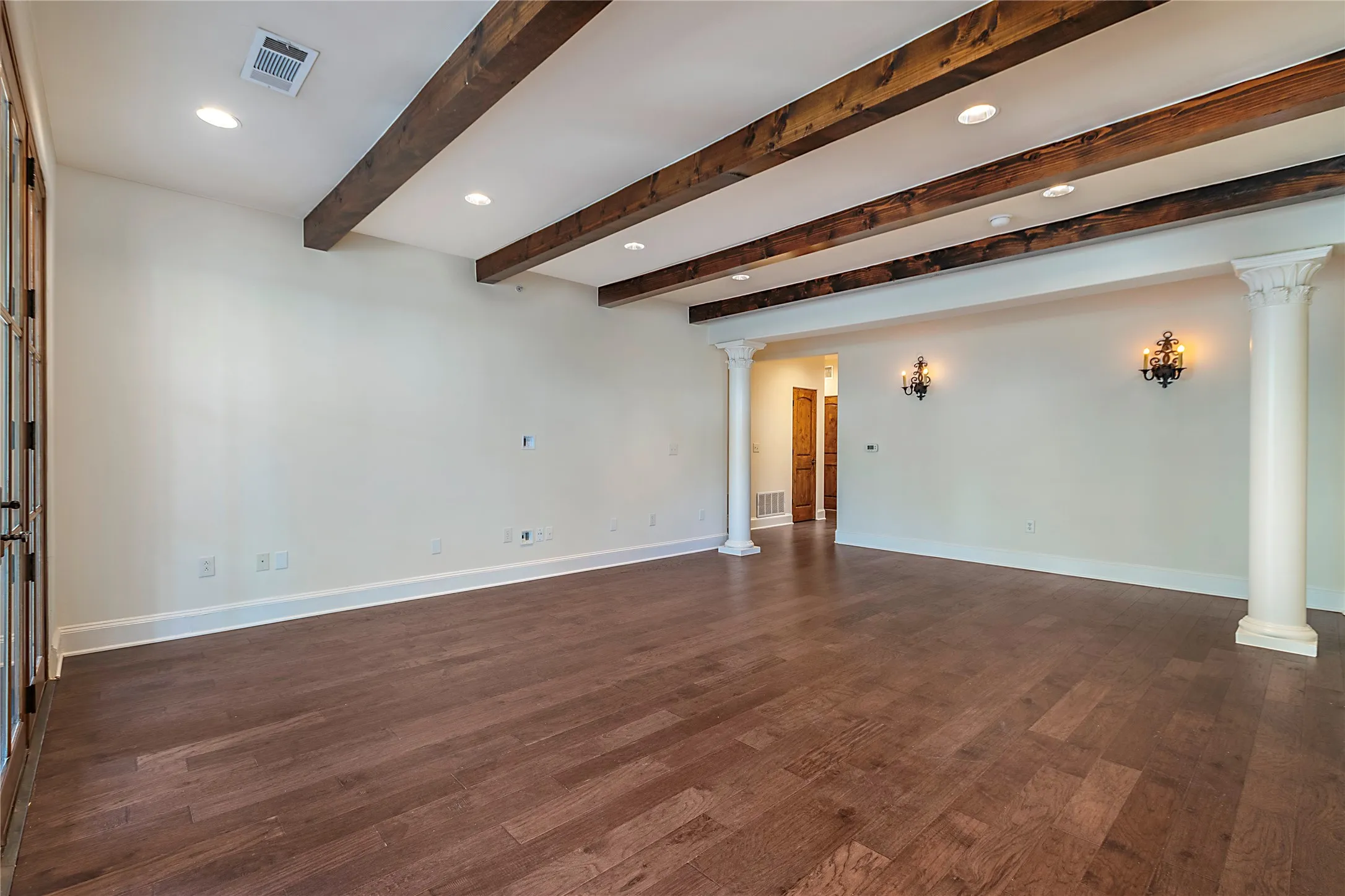 Spare room with beam ceiling, dark wood-type flooring, and ornate columns