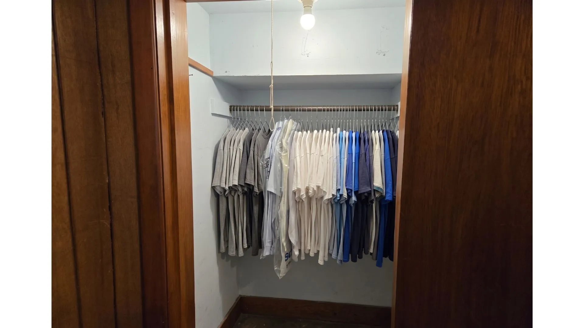 Closet space featuring a built-in hanging rod, overhead storage shelf, and wood trim details