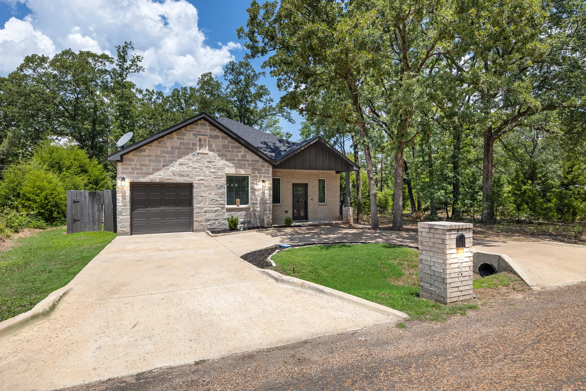 Stone veneer exterior featuring a dark asphalt shingle roof, attached garage, and a concrete driveway
